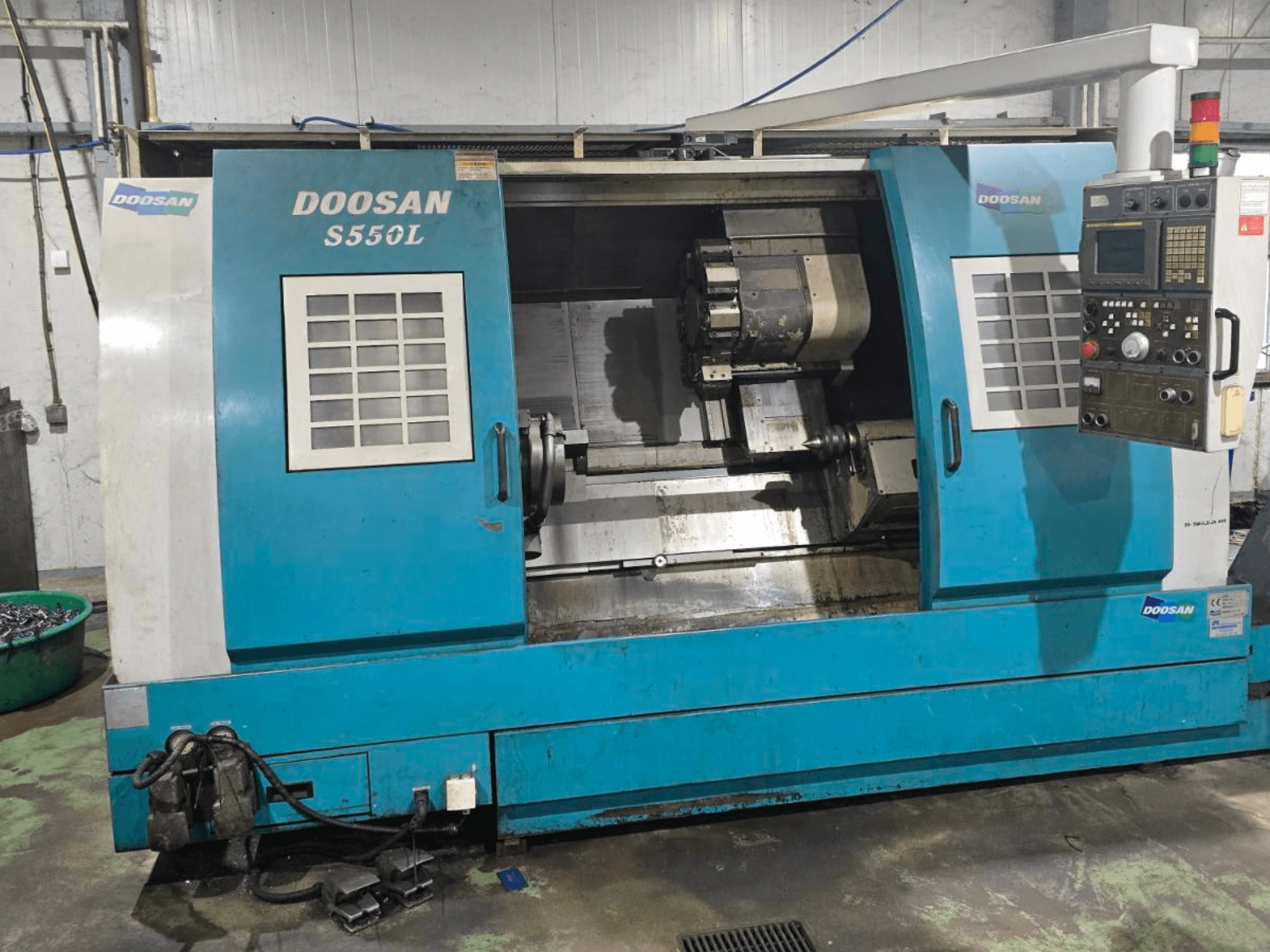 Torneiro horizontal DOOSAN S550L em vista lateral, com painel de controlo e base de torno, ideal para maquinação de precisão.
