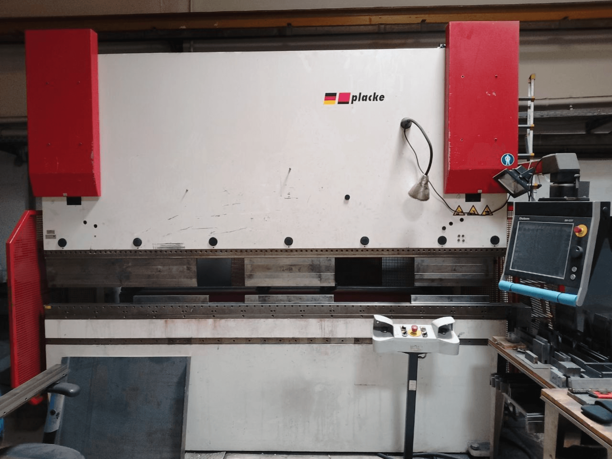 Prensa de dobra PLACKE QPB-4 150/3100, vista frontal que mostra o painel de controlo, os braços vermelhos e a área de dobra de metal.