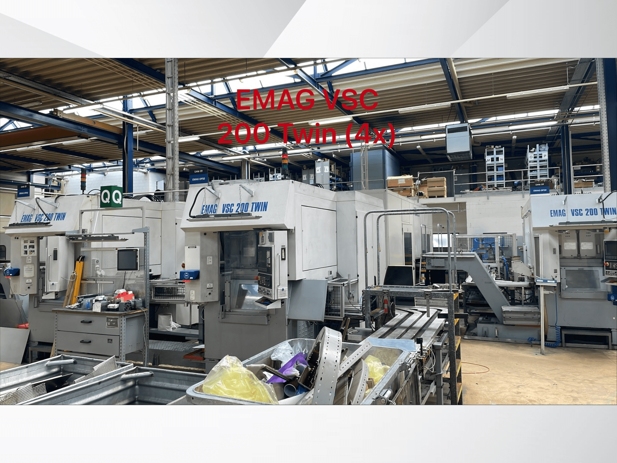 Vista frontal dos tornos verticais EMAG VSC 200 TWIN OP 20 numa oficina, mostrando várias unidades e equipamento circundante.