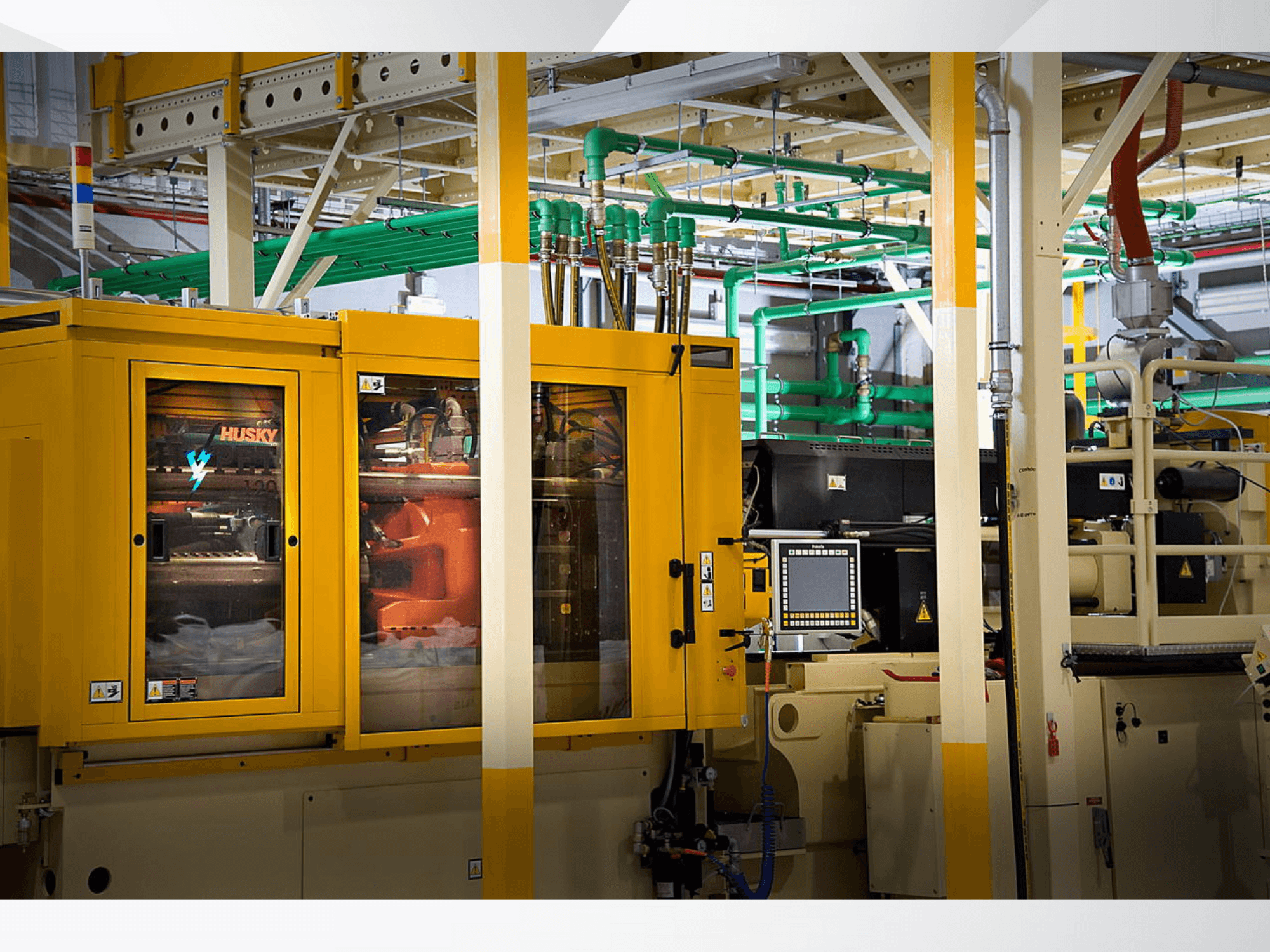 Máquina industrial Husky em amarelo, vista frontal mostrando o painel de controlo e os mecanismos internos num cenário de fábrica.