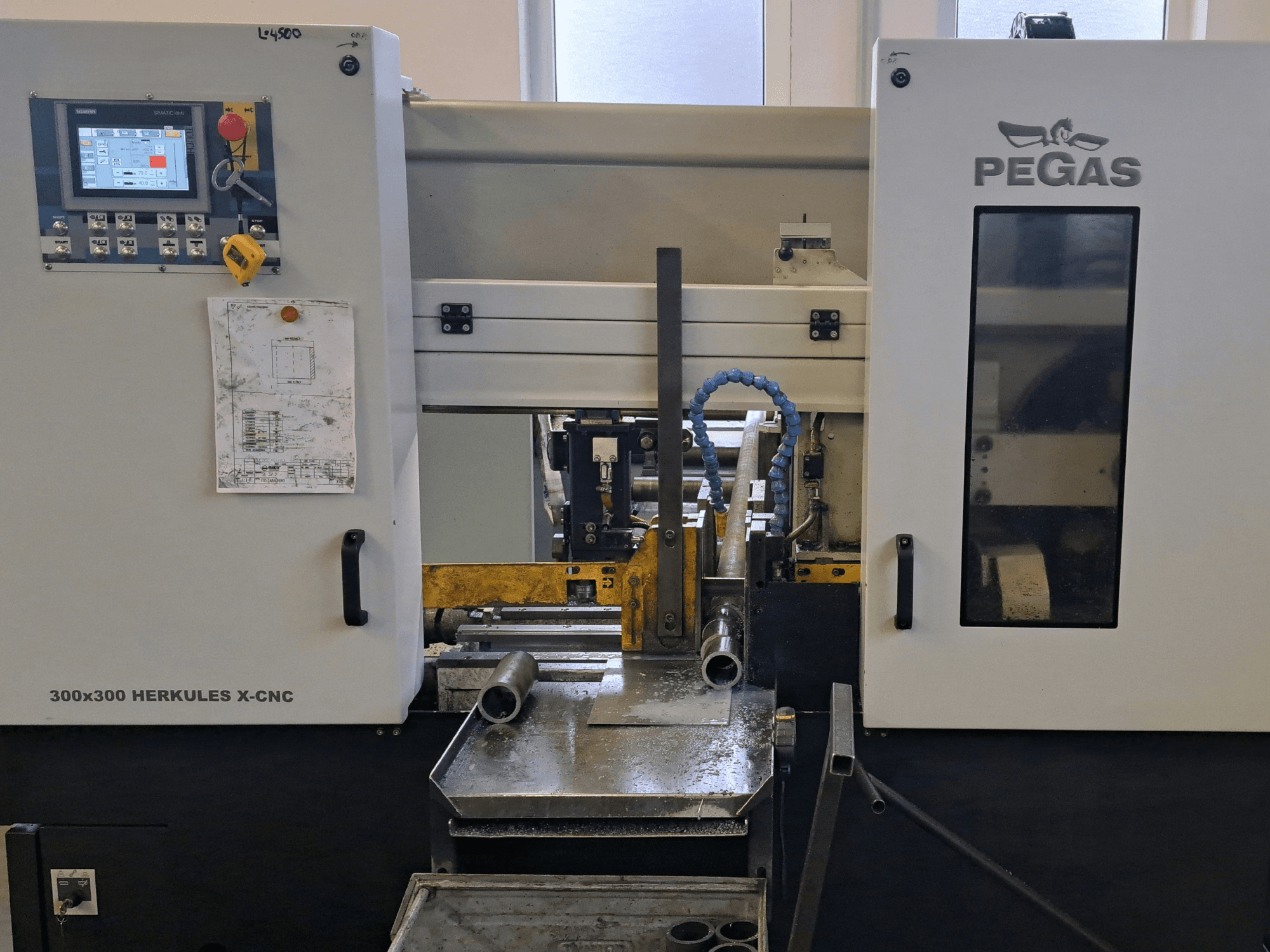Máquina para chapas metálicas Pegas HERKULES X-CNC 300x300, vista frontal, mostrando o painel de controlo e a área de trabalho com peças metálicas.