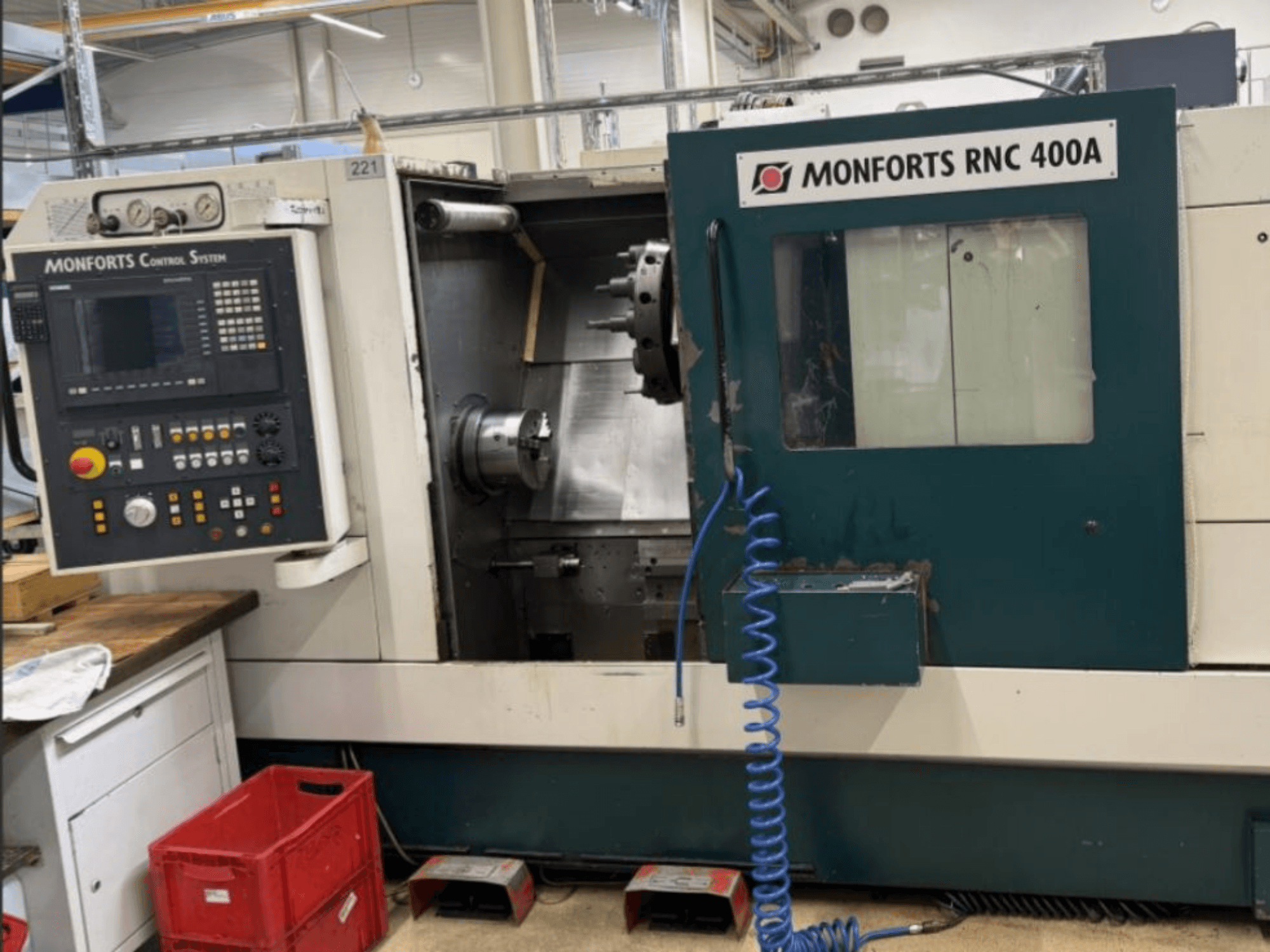 Monforts RNC 400 A, virador horizontal, vista frontal, mostrando o painel de controlo e a área de trabalho com caraterísticas em destaque.