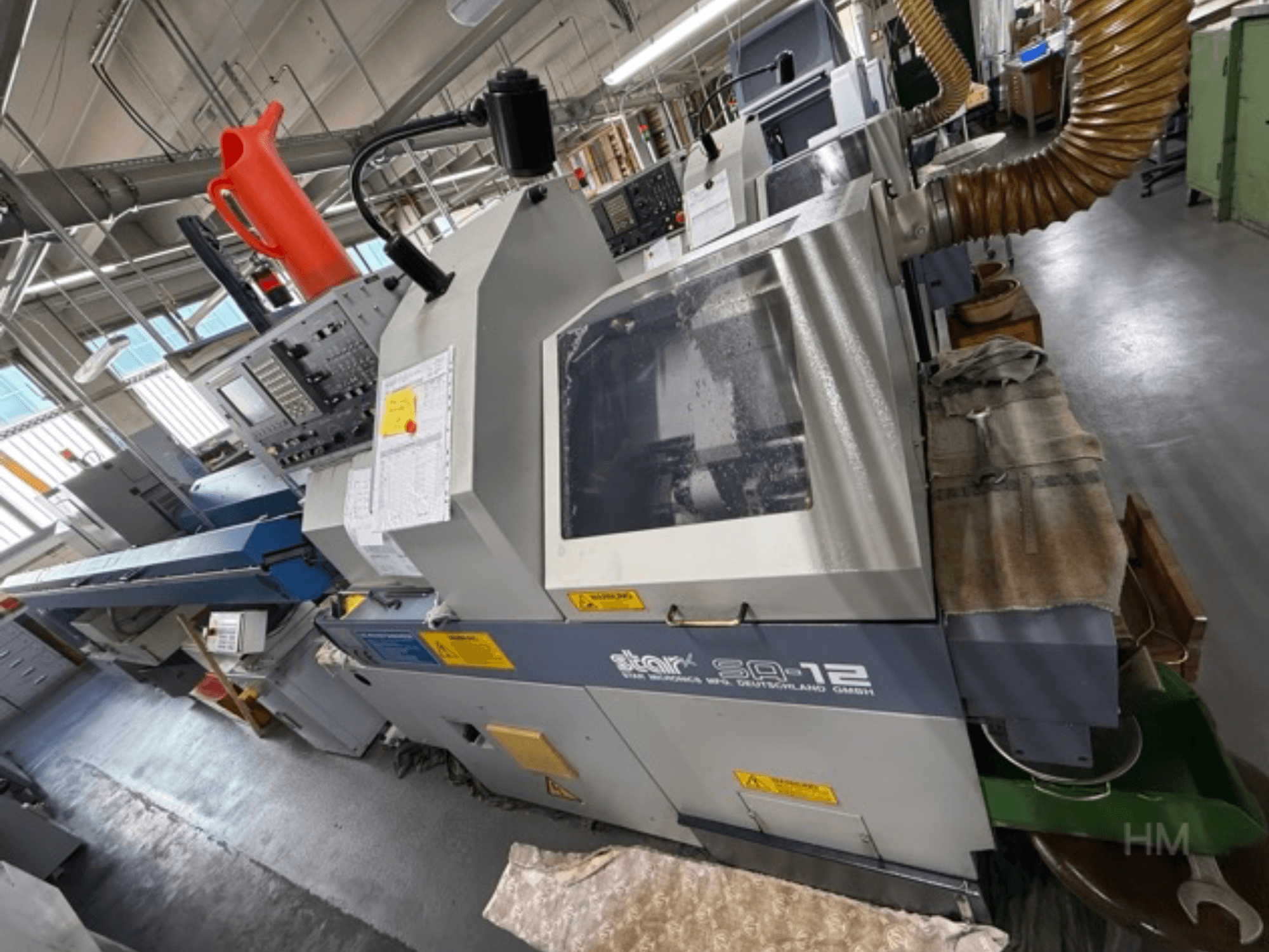 Centro de maquinação Star SQ-12, vista lateral com painel de controlo, recipiente de refrigeração e mangueira de extração de poeiras visíveis.