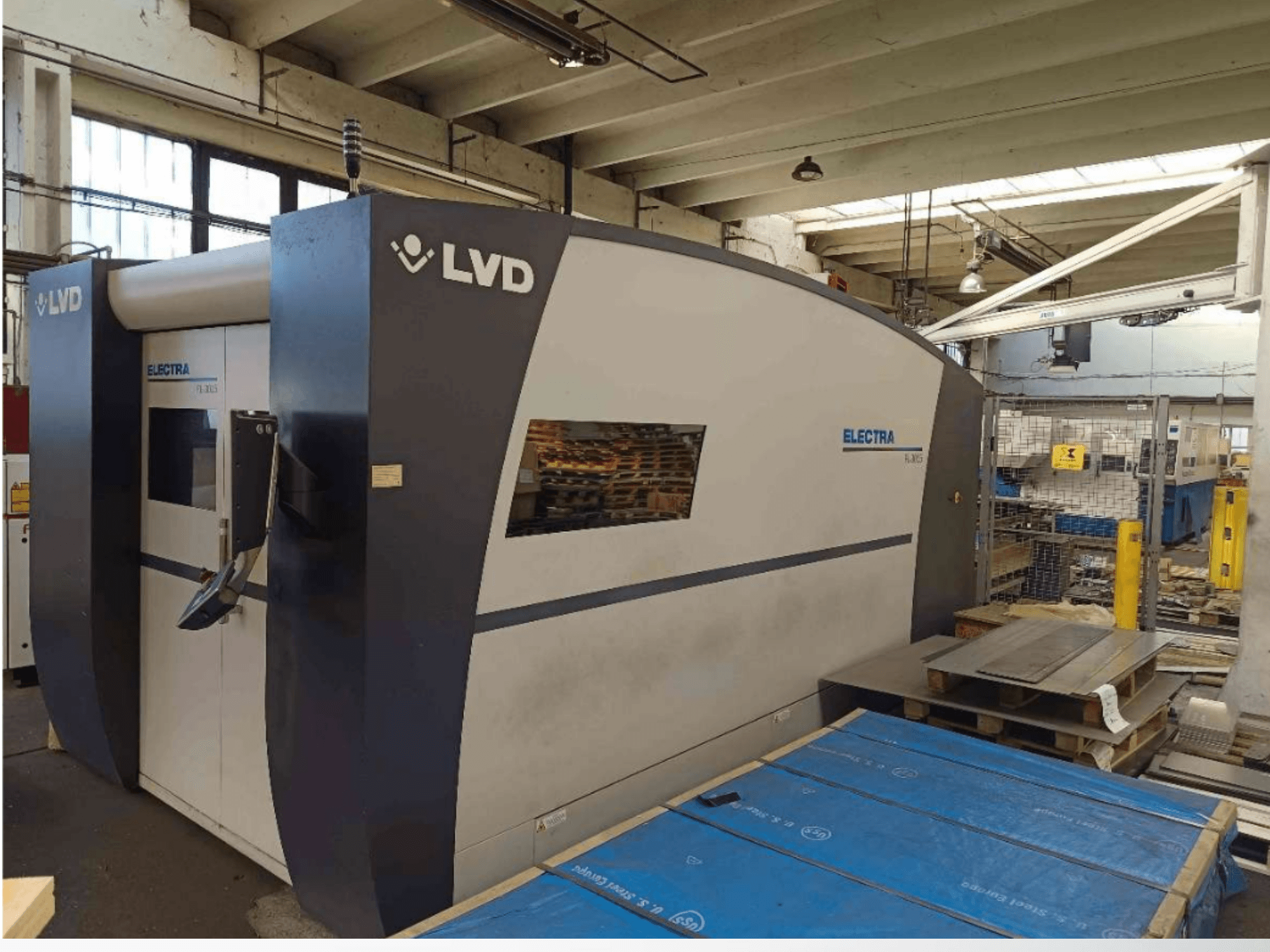 Máquina de corte a laser LVD Electra em vista lateral, com um design elegante e um painel de controlo na porta, colocada numa oficina.