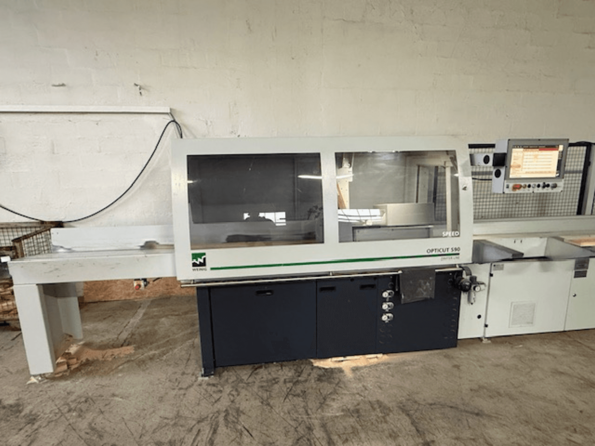 WEINIG OPTICUT S90, serra de corte transversal optimizada, vista frontal mostrando o painel de controlo, a unidade de serra e a mesa de alimentação.