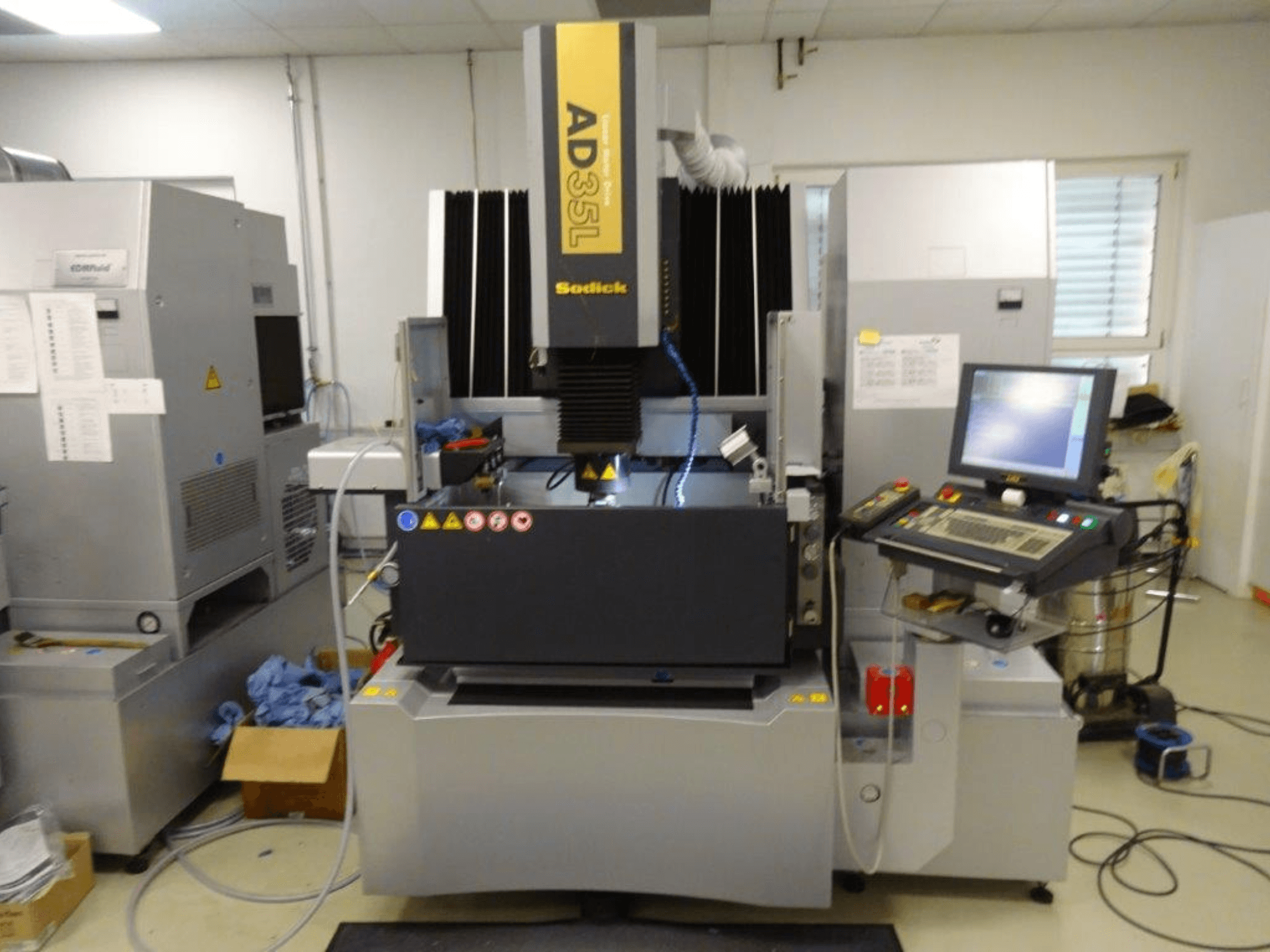 Máquina de descarga eléctrica Sodick AD35L, vista frontal com painel de controlo, sistema de arrefecimento e área de trabalho visíveis.