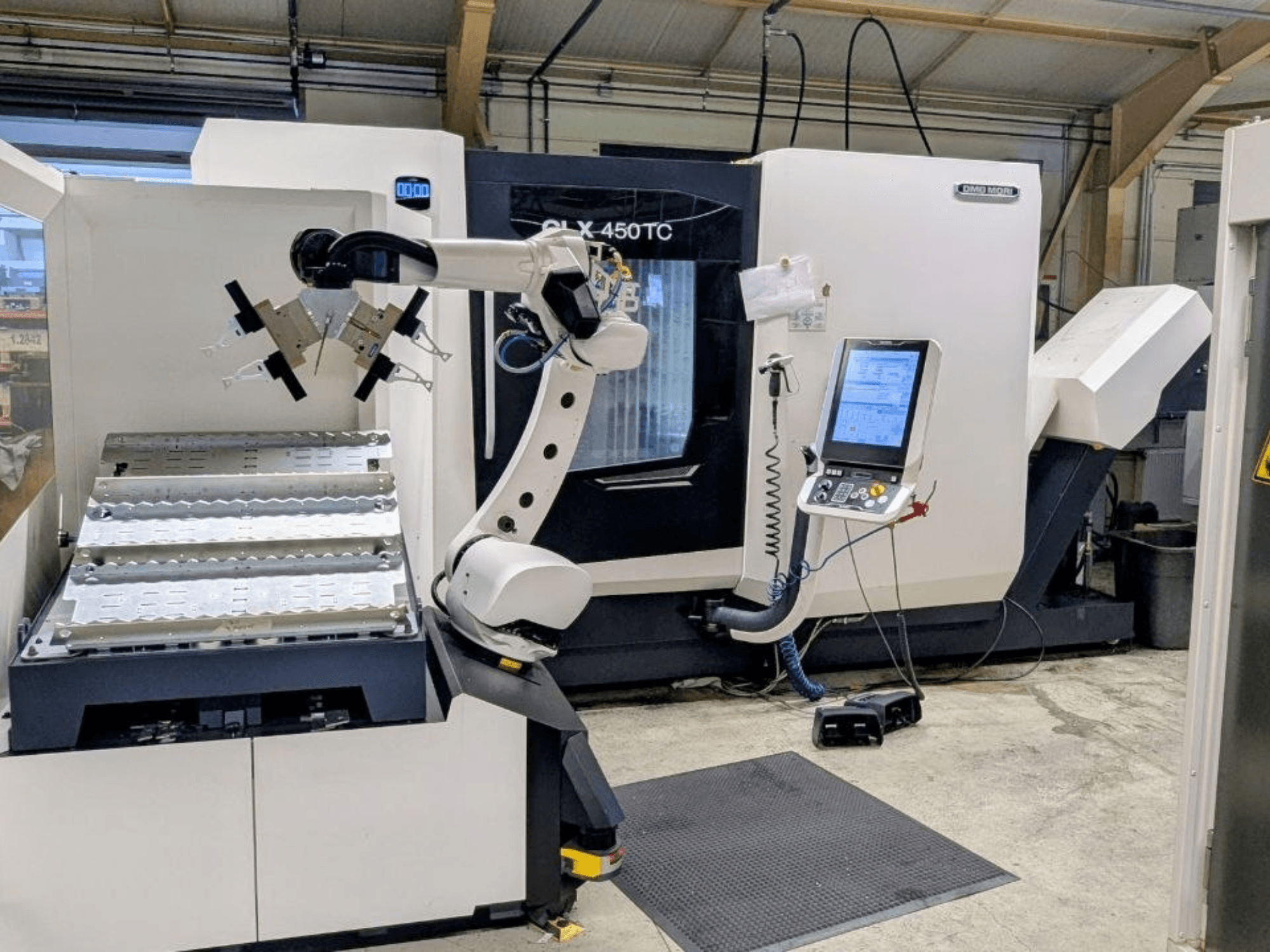 DMG MORI CLX 450 TC com Robo2go, vista frontal, mostrando o braço robótico e o painel de controlo ao lado da máquina.