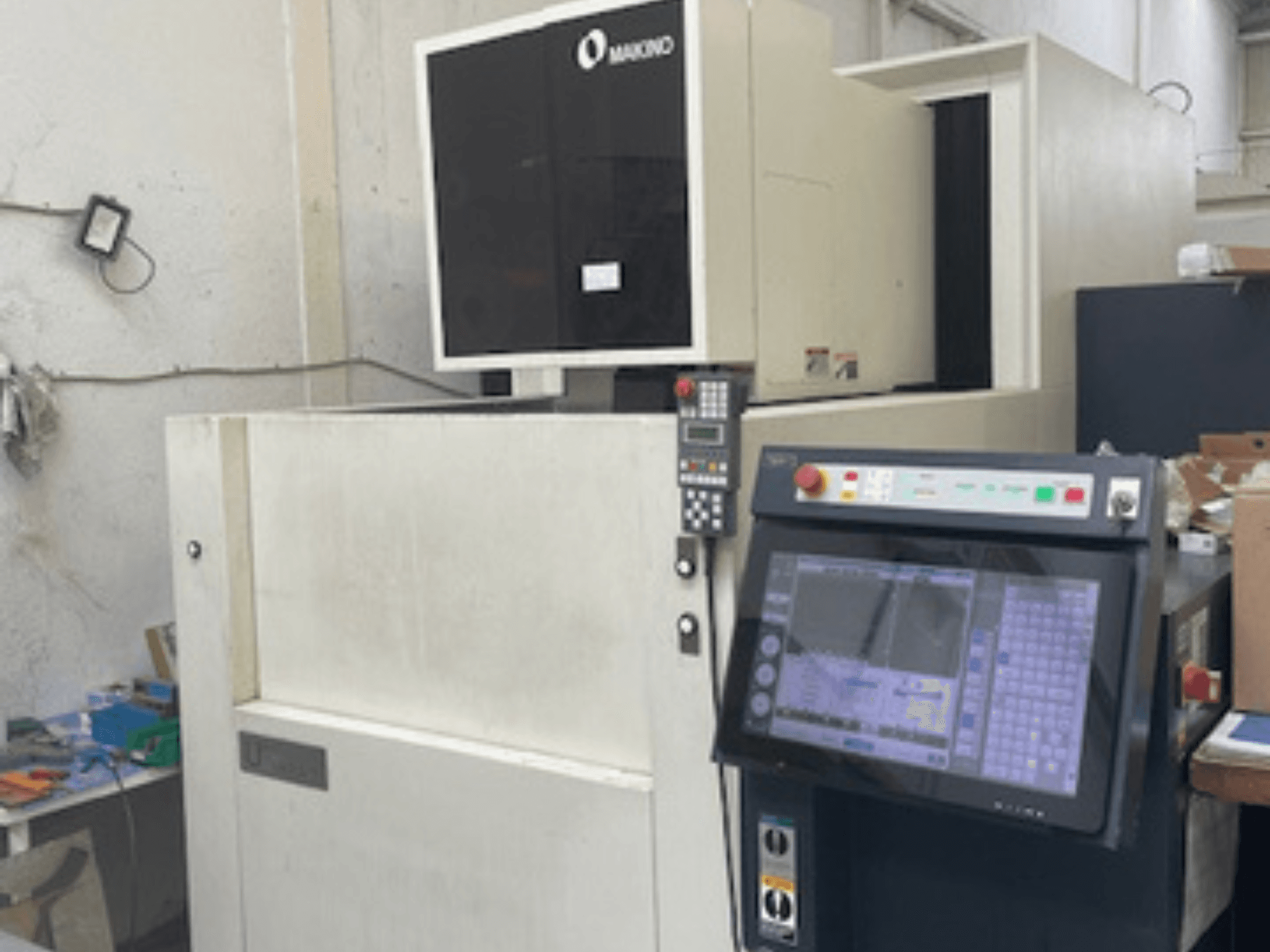Máquina EDM de fio Makino U6 HEAT numa oficina, vista frontal mostrando o painel de controlo e o visor digital.