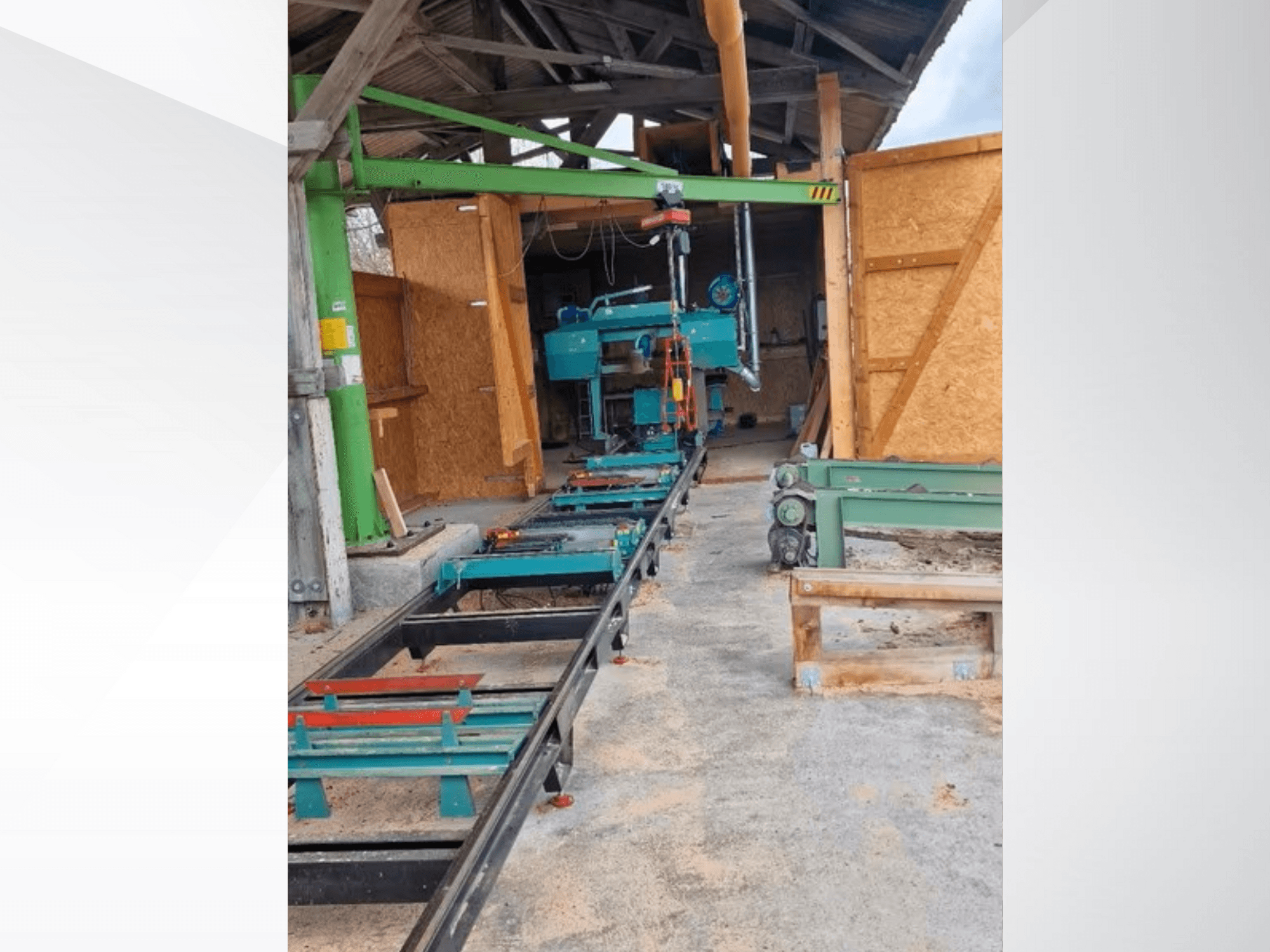 Máquina de serra de fita horizontal na oficina, vista de frente. O equipamento inclui uma calha e acessórios verdes adicionais.