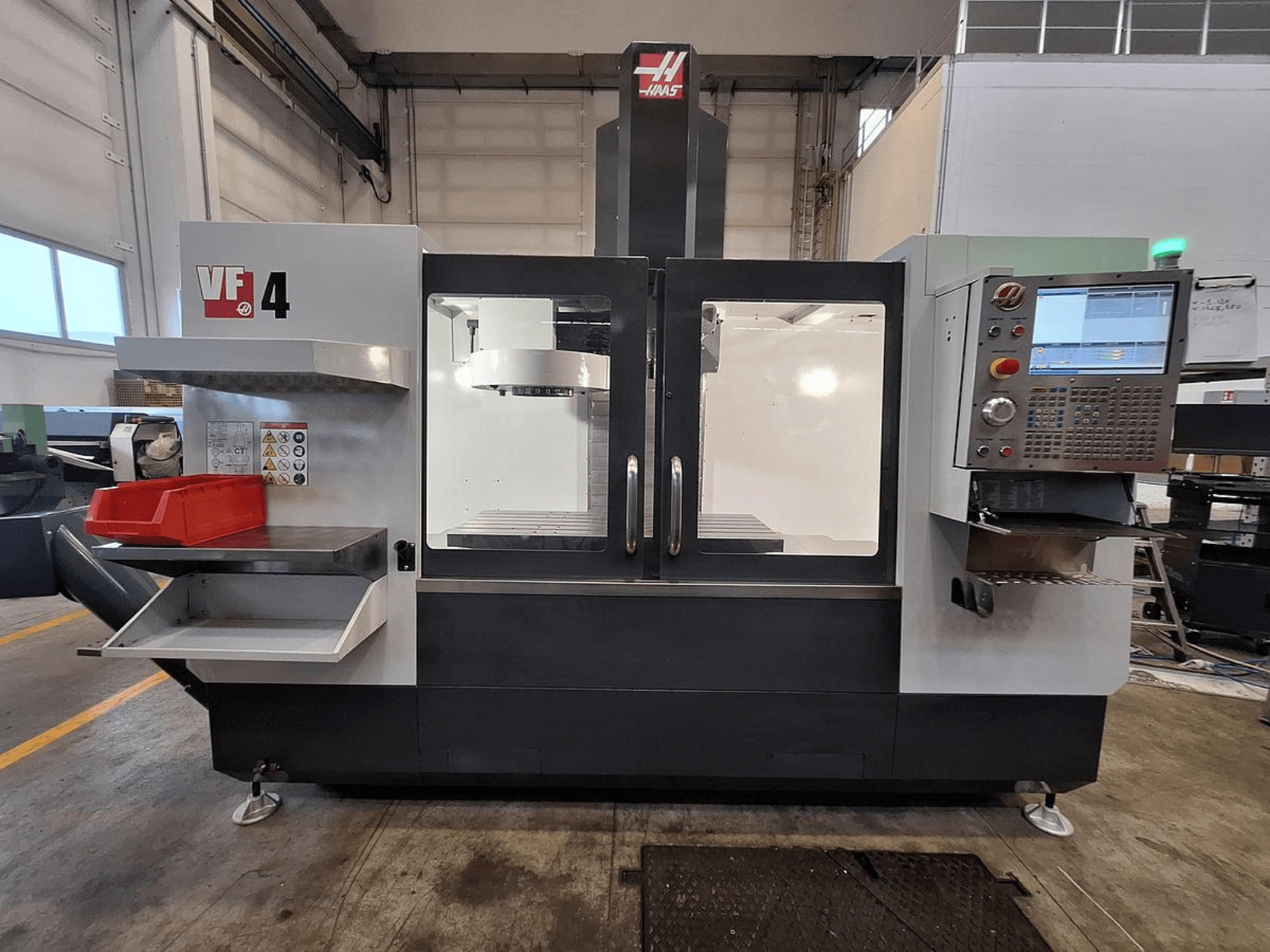 Centro de maquinação vertical Haas VF-4, vista frontal, com um painel de controlo, suporte de ferramentas e área de trabalho espaçosa.
