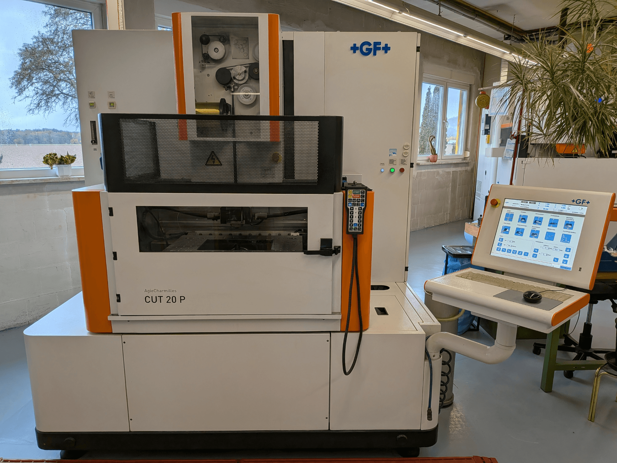 Máquina de eletroerosão por fio AgieCharmilles Cut-20 P, vista de frente, com painel de controlo e ecrã, instalada numa oficina bem iluminada.