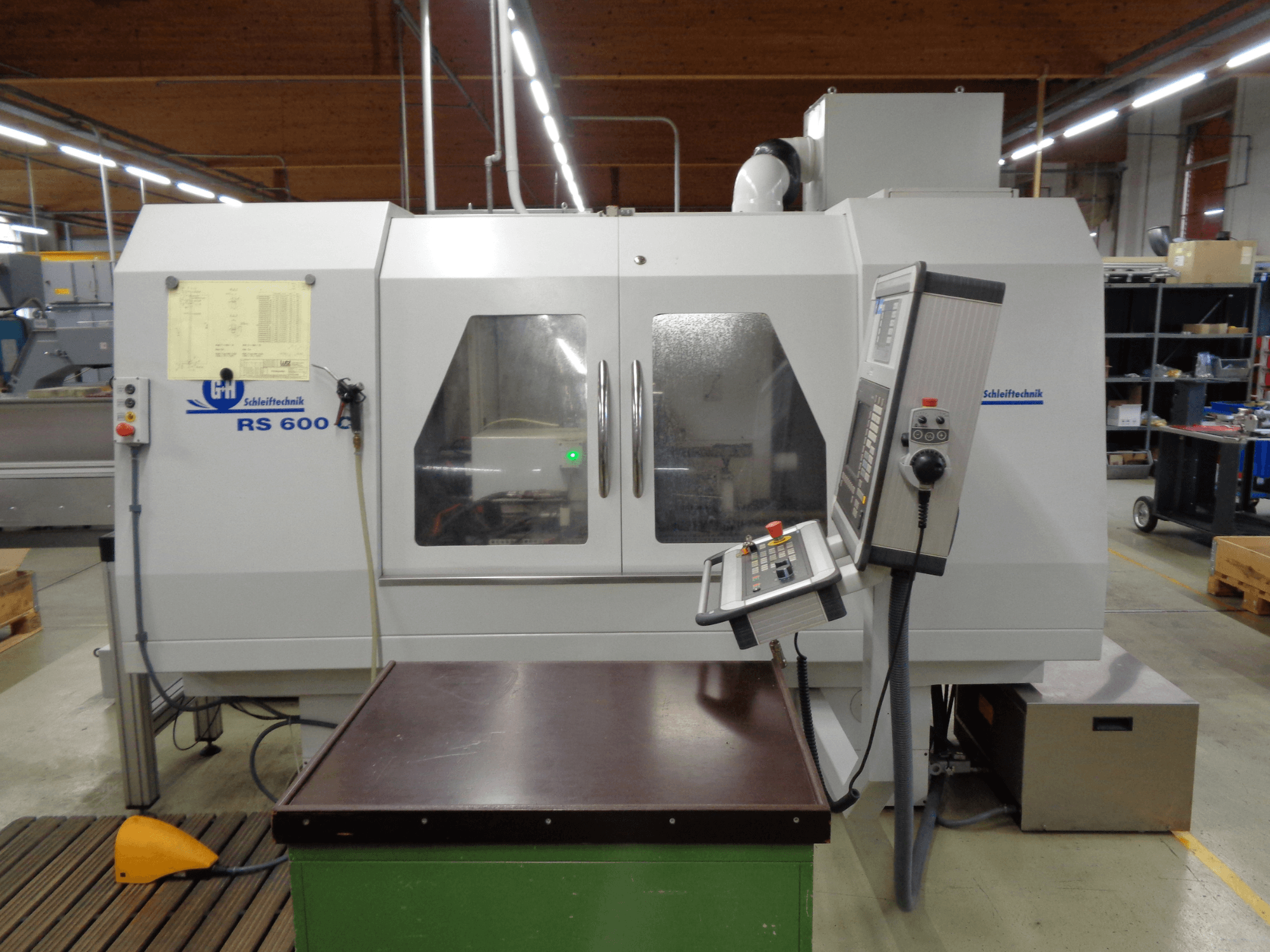 Máquina de retificação cilíndrica GEIBEL & HOTZ RS 600 C, vista frontal mostrando o painel de controlo e a mesa de trabalho numa fábrica.