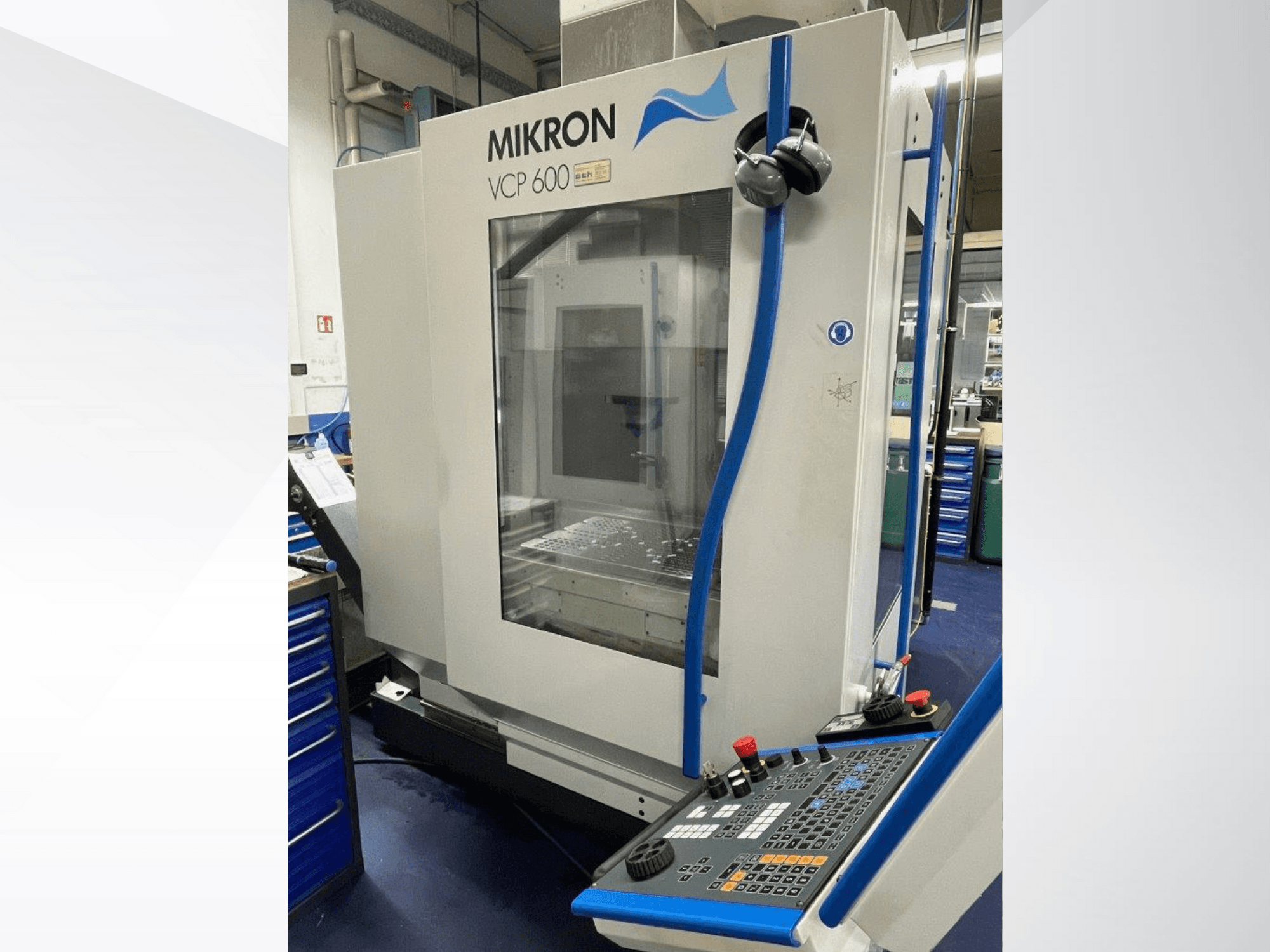 Centro de maquinação Mikron VCP 600 numa oficina, vista frontal, com um painel de controlo com botões e botões.