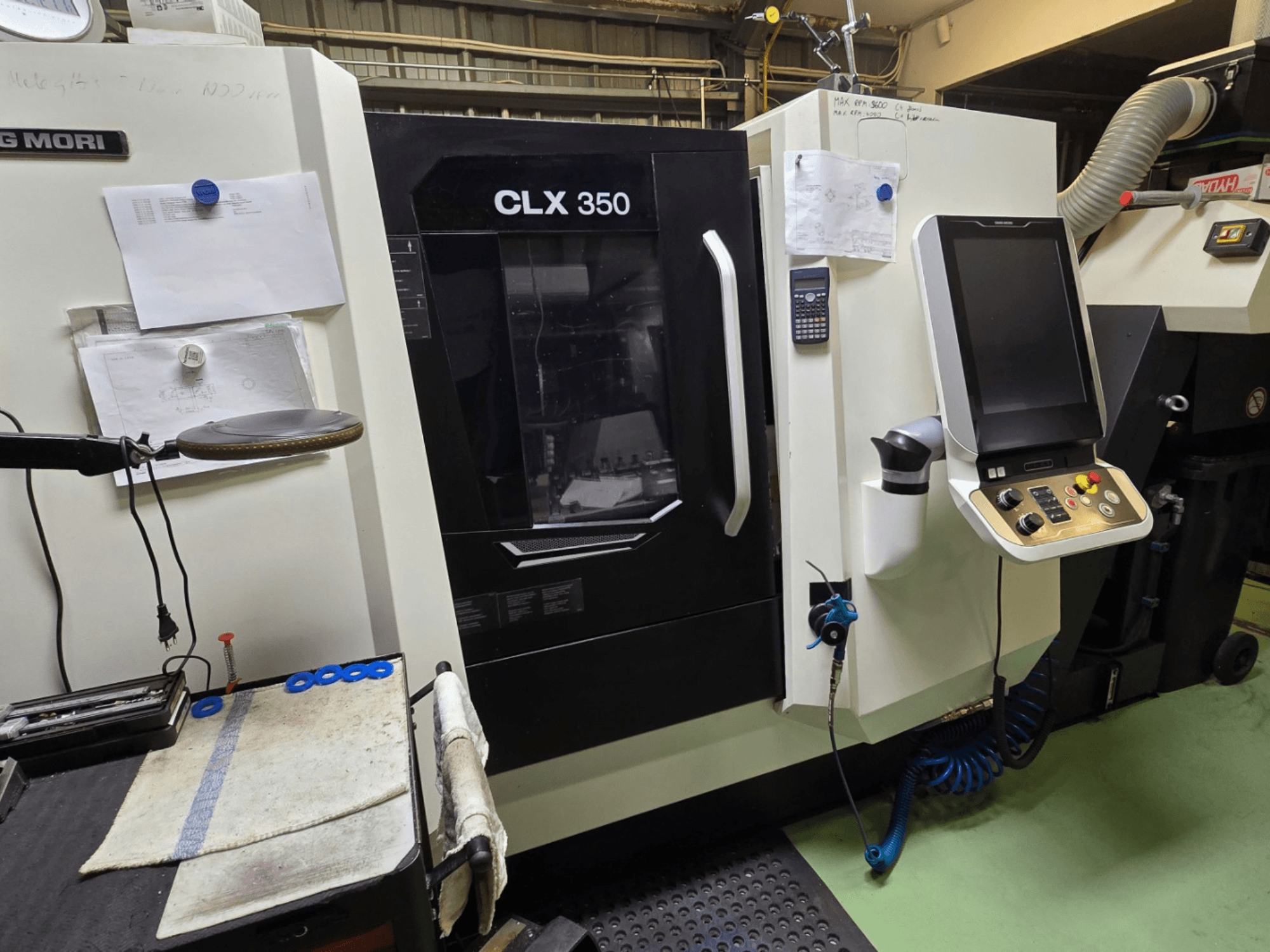 Torno CNC DMG MORI CLX 350 numa oficina; vista frontal com painel de controlo, ferramentas e espaço de trabalho visíveis.