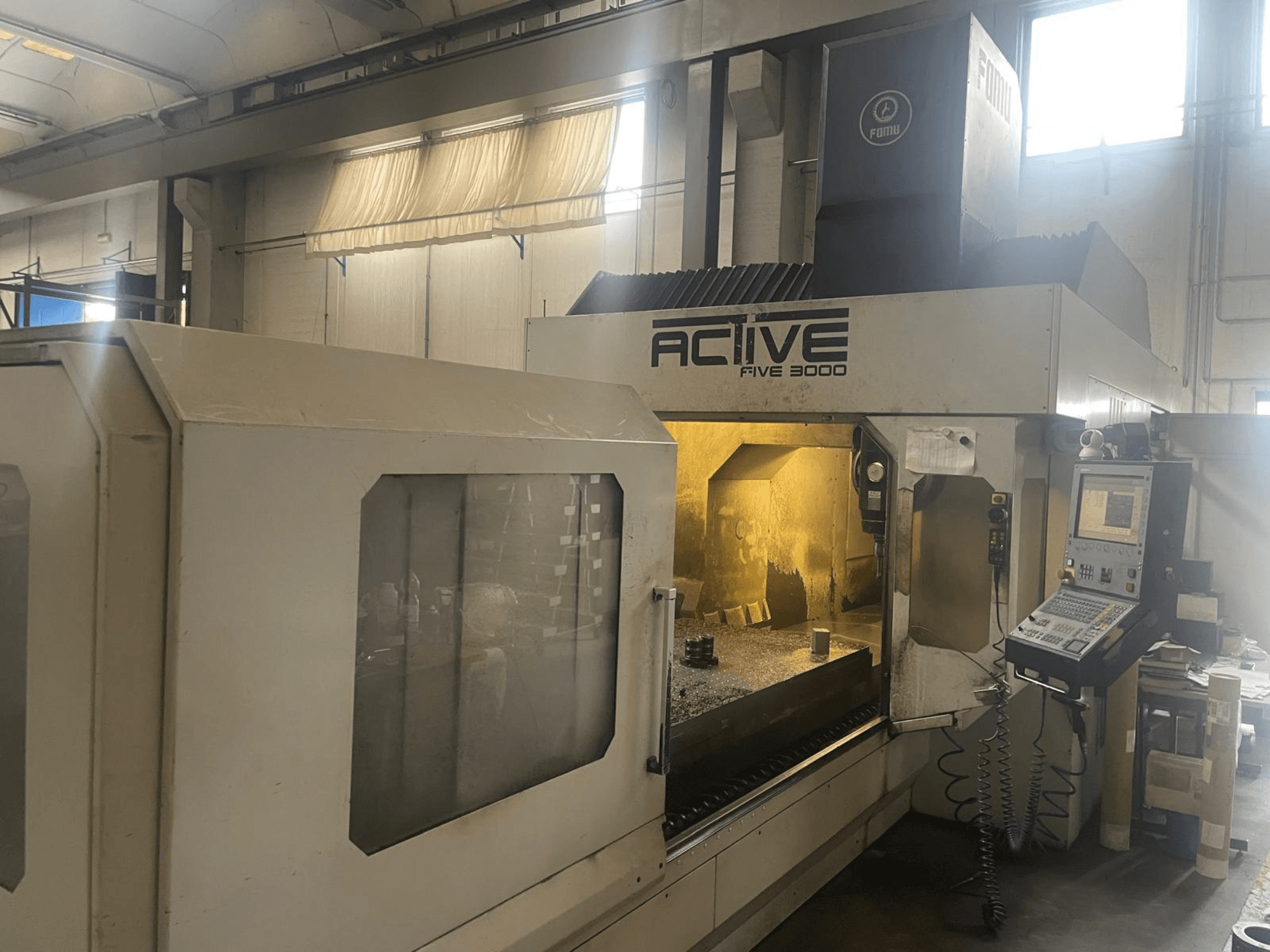 Vista frontal da máquina CNC ACTIVE Five 3000, mostrando o painel de controlo e a área de trabalho com uma peça parcialmente maquinada no interior.