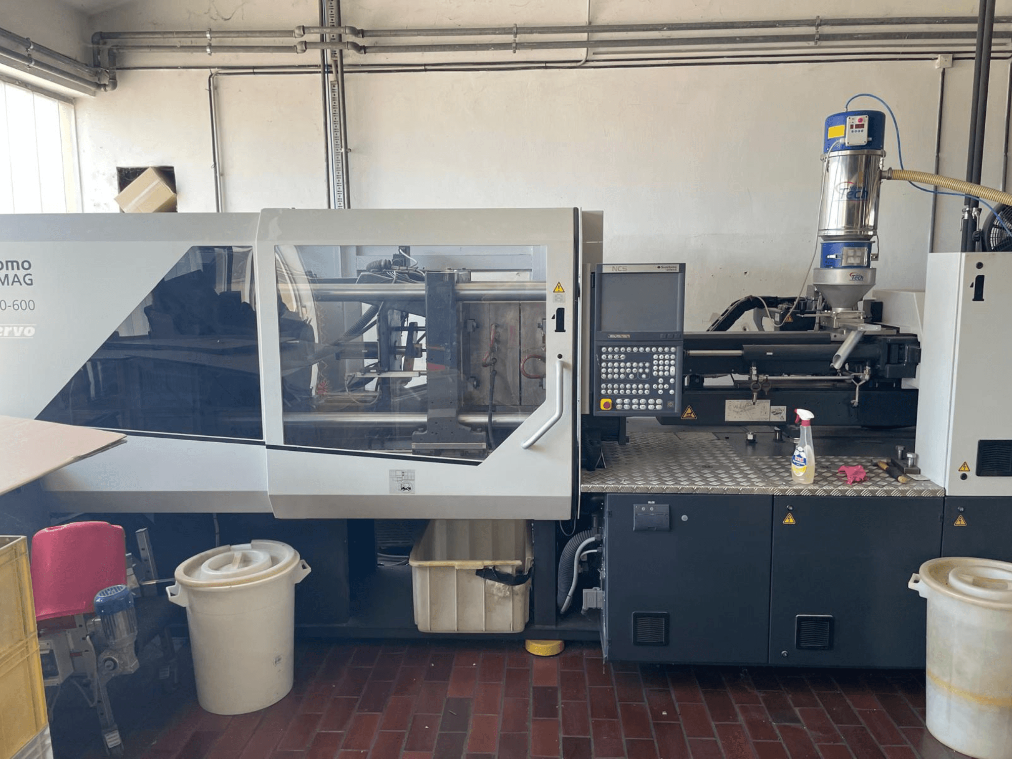 Vista frontal da máquina de moldagem por injeção hidráulica SUMITOMO SHI DEMAG Systec 160/520-600 com painel de controlo e unidade de alimentação.