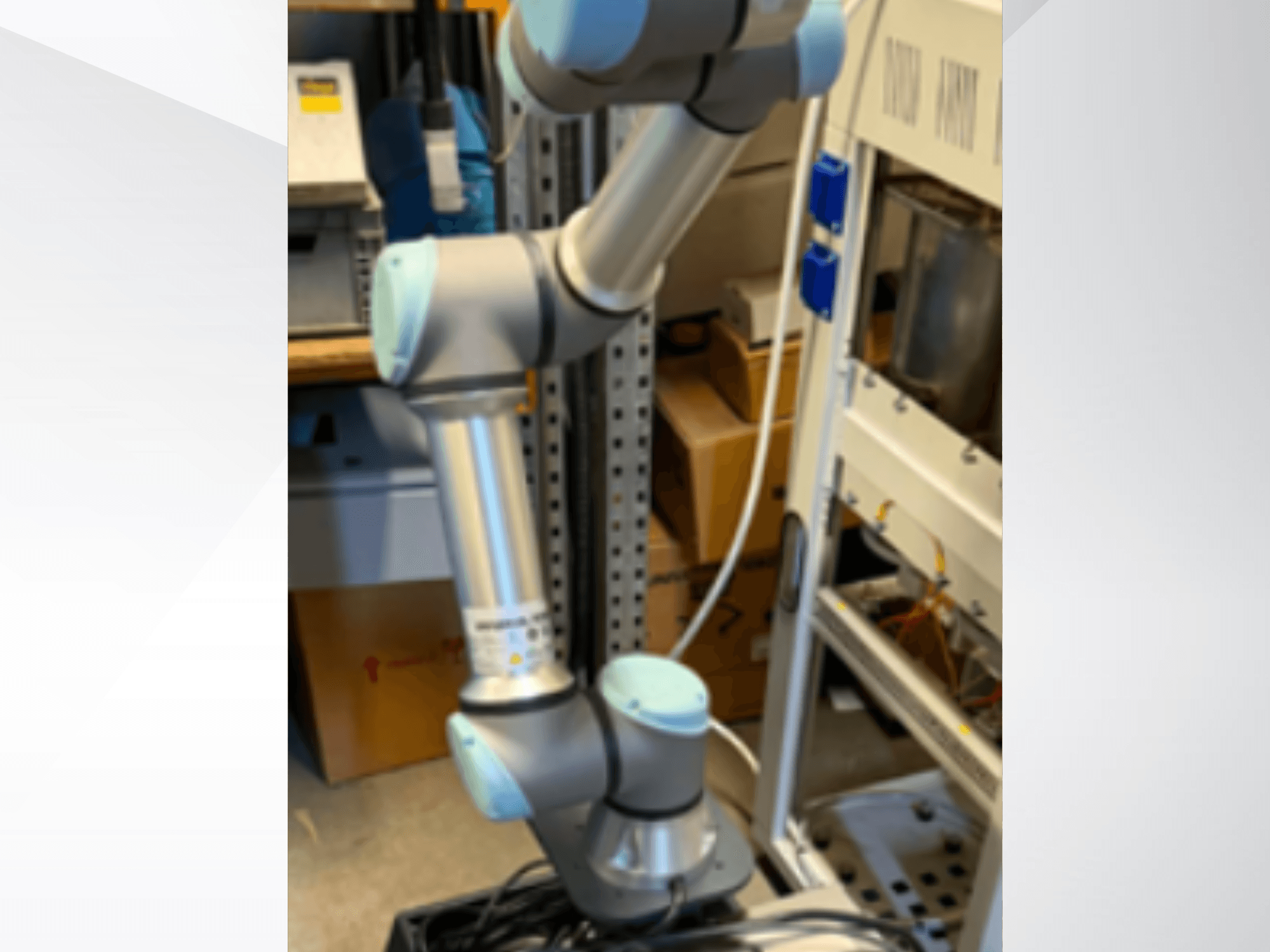 Braço robótico UR5e da Universal Robots visto de lado, mostrando as articulações, o design leve e os cabos de controlo.