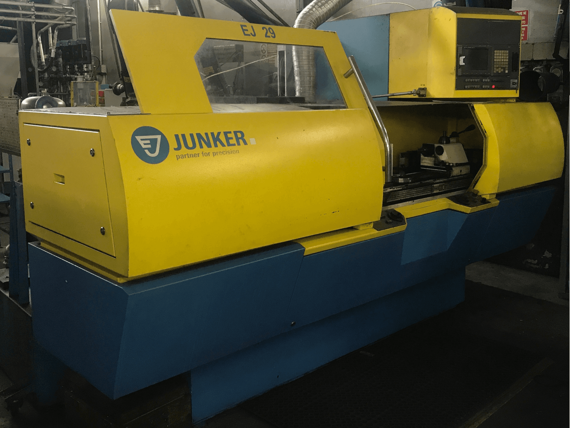 Rectificadora JUNKER EJ 29, vista frontal, com caixa amarela e azul, painel de controlo e componentes internos visíveis.