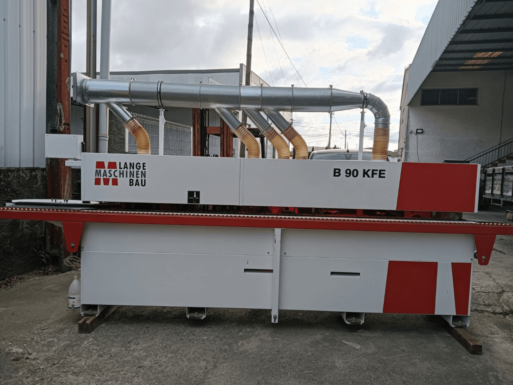 Máquina de encanção LANGE Maschinenbau B 90 KFE, vista lateral, com tubos de escape duplos e detalhes em vermelho, instalada num espaço de trabalho industrial.