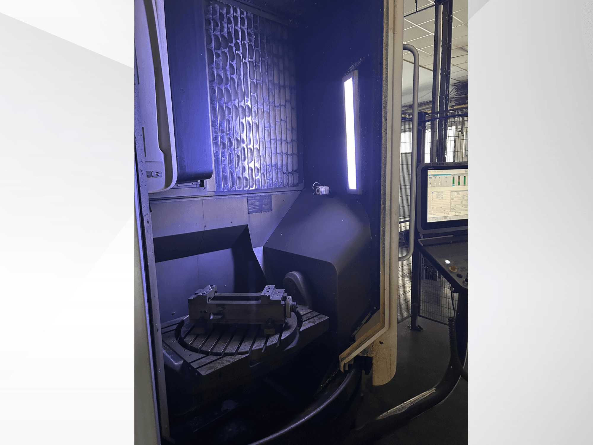 Centro de maquinagem vertical DMG MORI DMU 65 MonoBlock, vista frontal que mostra a mesa rotativa com a peça de trabalho e o painel de controlo.