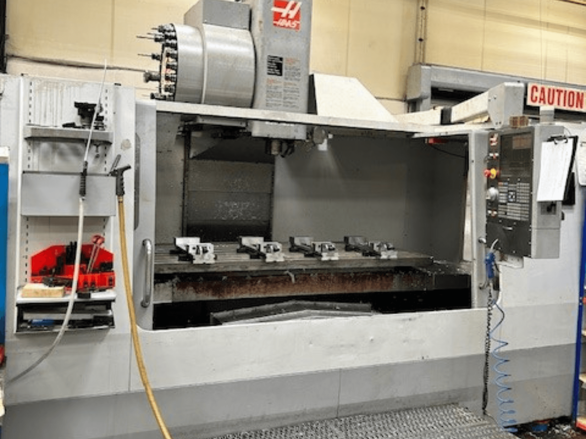 Centro de maquinação vertical HAAS VF-9/40HE, vista frontal, com suporte de ferramentas e acessórios visíveis na lateral.