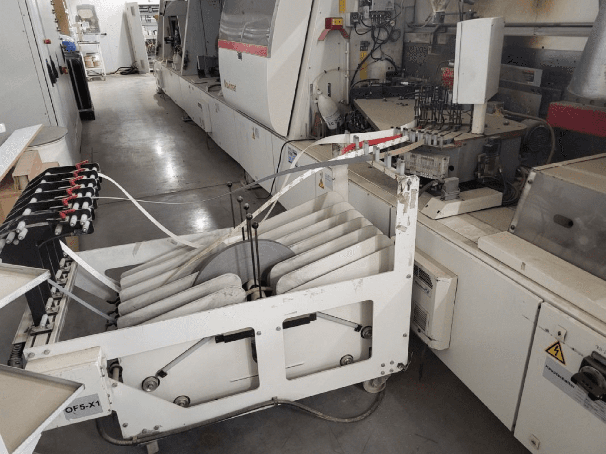 Lixadeira de bordos IMA Novimat/I/680/650/R3, vista lateral mostrando os rolos de alimentação e o painel de controlo em ambiente de oficina.
