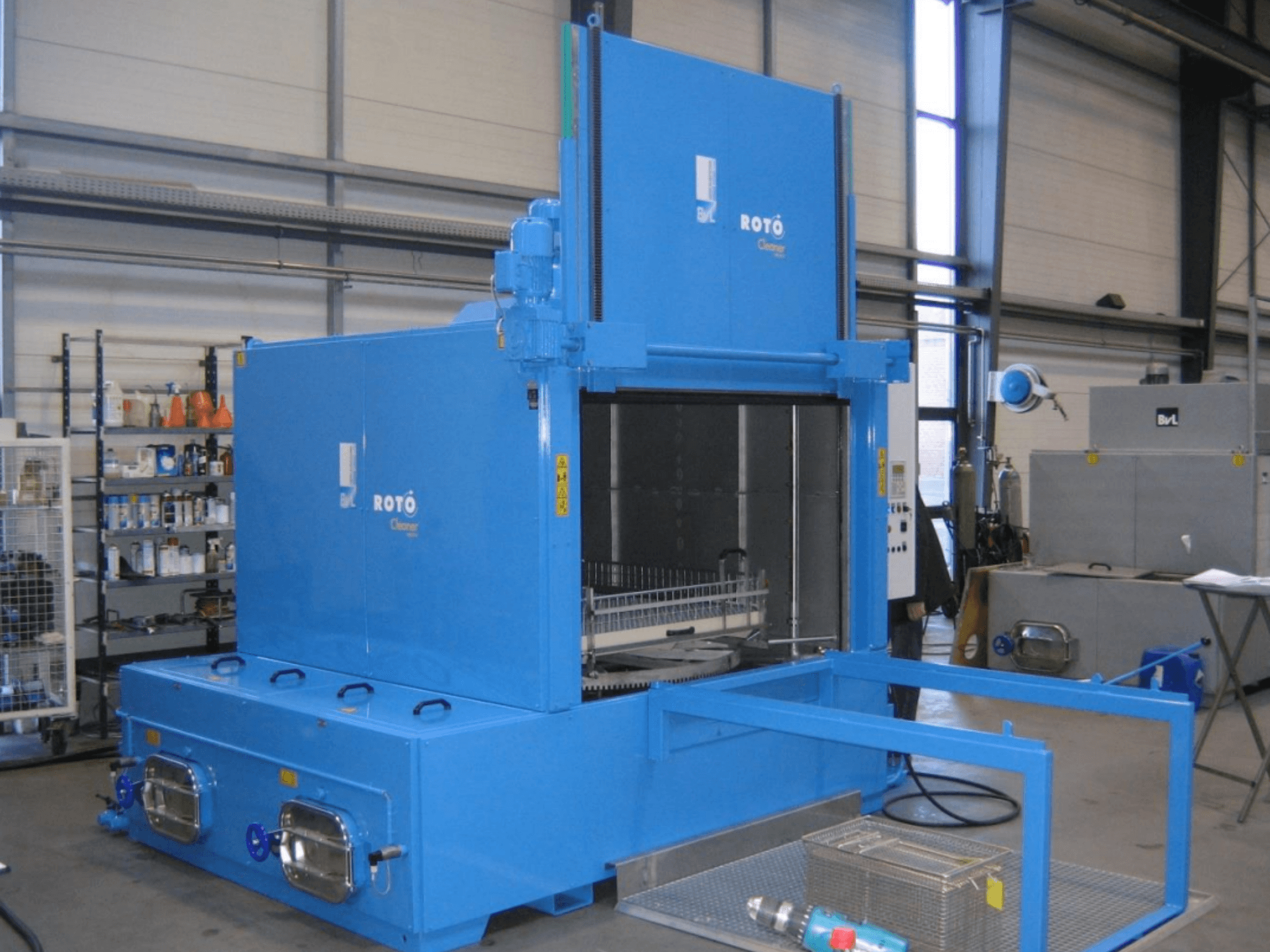 Máquina-ferramenta BVL RC 1950 RW 2T em azul, vista frontal, mostrando a entrada da máquina de limpeza e o cesto para peças.