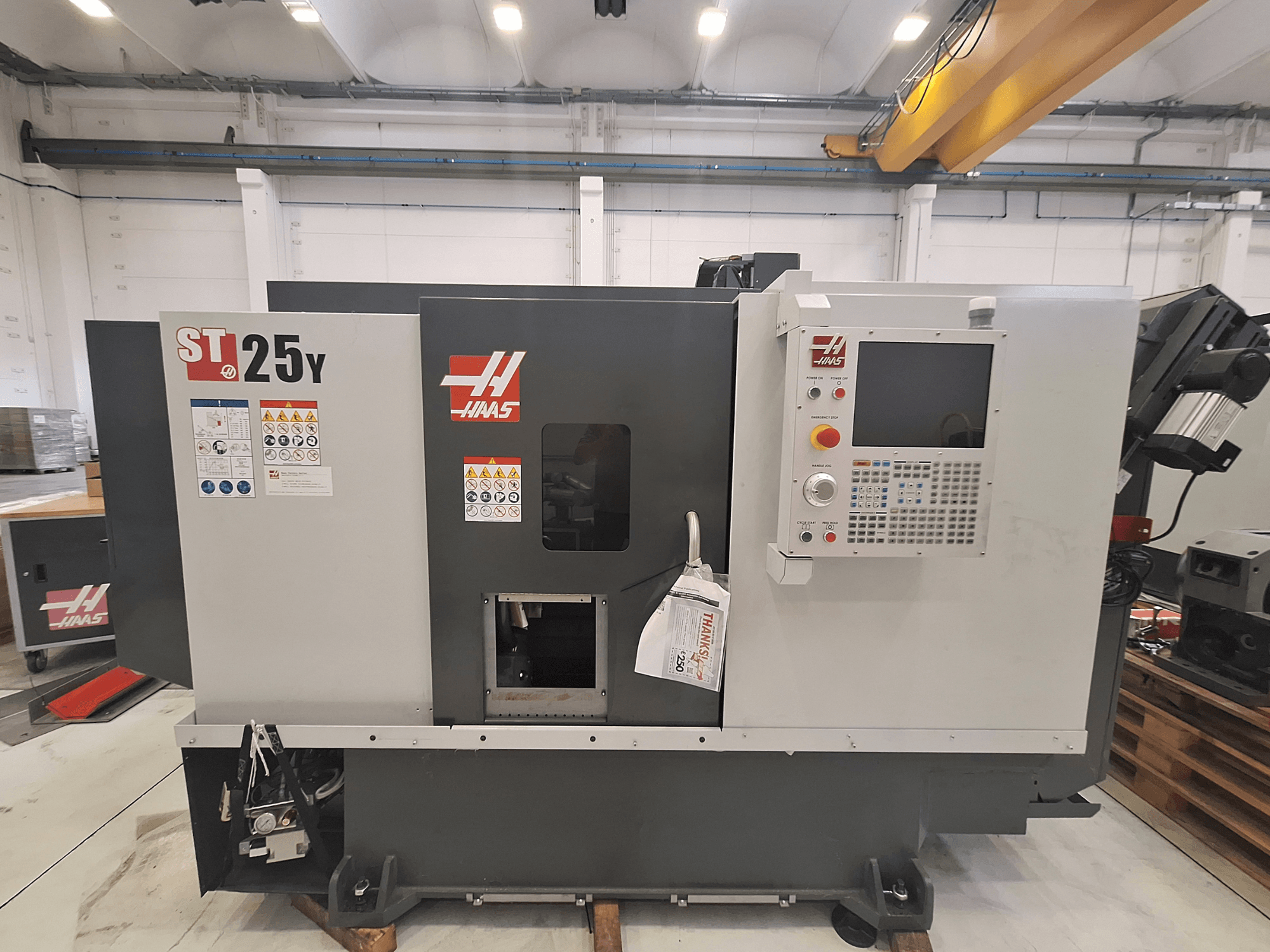 Torno horizontal Haas ST-25Y, vista frontal, com painel de controlo e etiquetas de segurança. Ideal para usinagem de precisão.