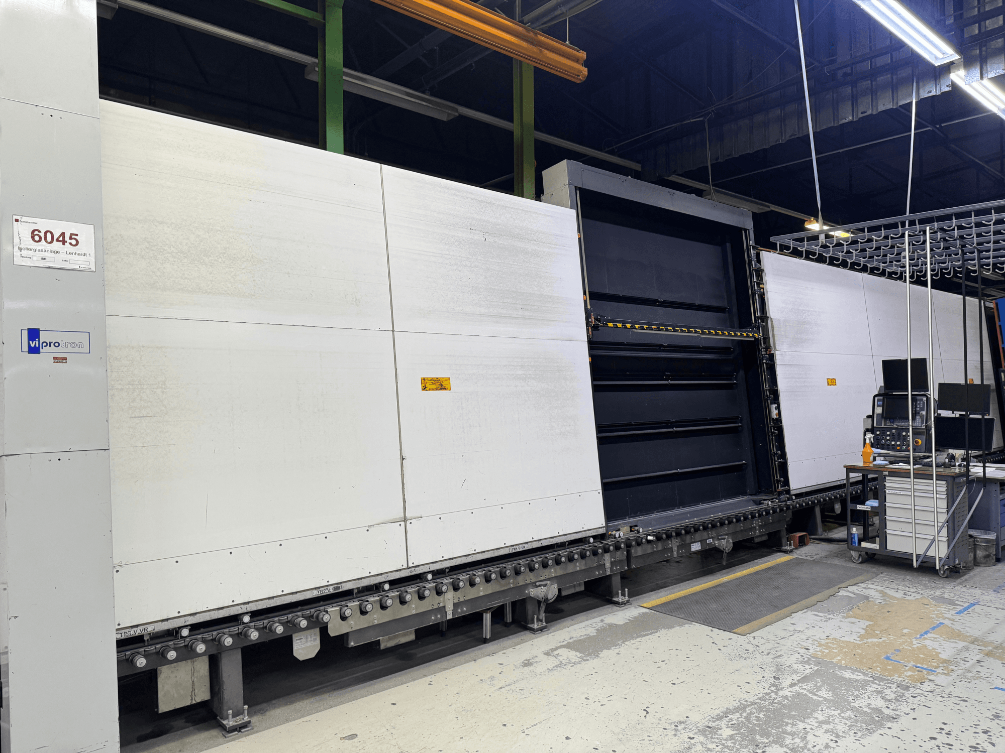 Vista frontal da máquina de moldes Vipro com painel aberto, mostrando o equipamento operacional e um espaço de trabalho ao lado. Modelo 6045.