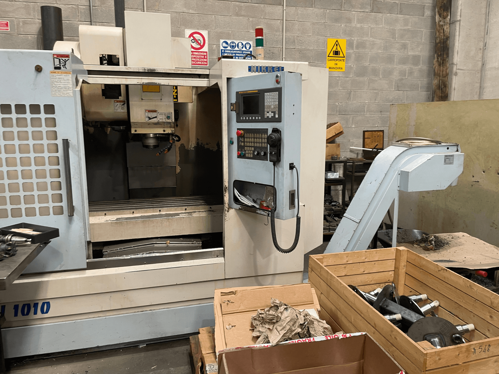 Centro de maquinação vertical da marca Other, modelo VH-1010, visto de frente com os comandos visíveis e caixas próximas.