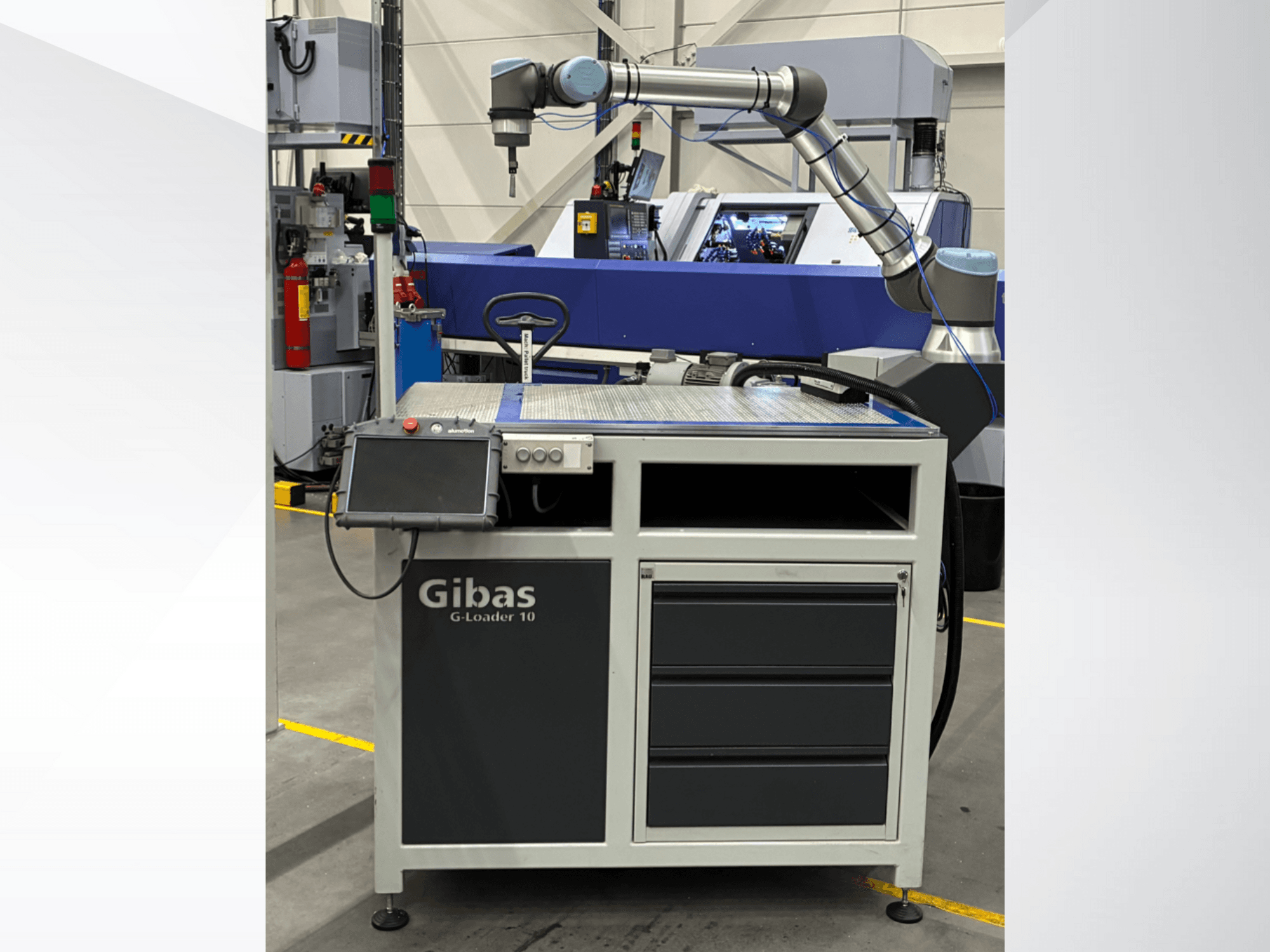 Gibas G-Loader 10 com braço robótico, vista frontal; possui controlo por ecrã tátil e arrumação de gavetas em ambiente industrial.