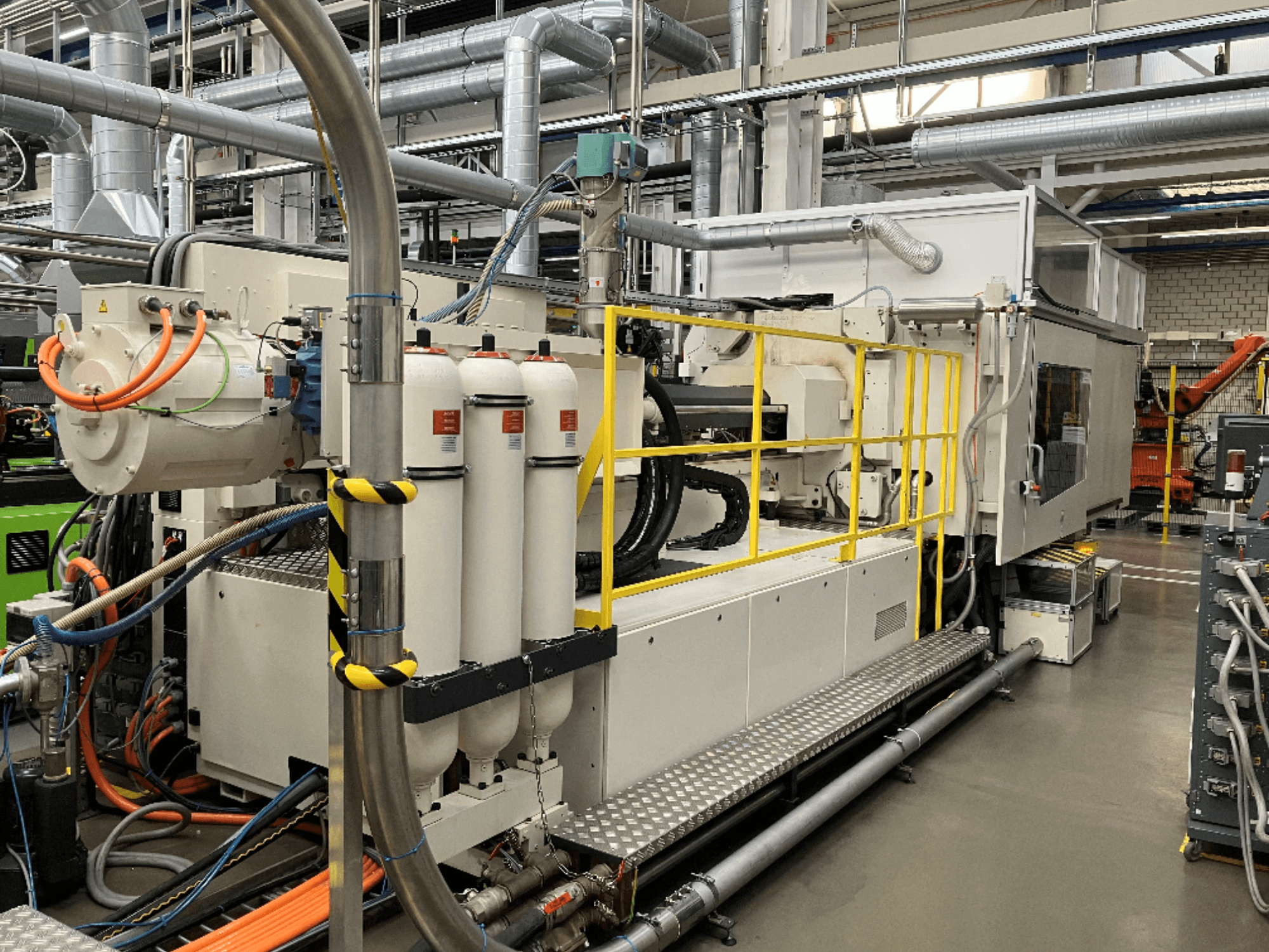 Máquina industrial com caixa branca e cinzenta, várias mangueiras e tanques de filtragem; vista lateral mostrando a configuração operacional.