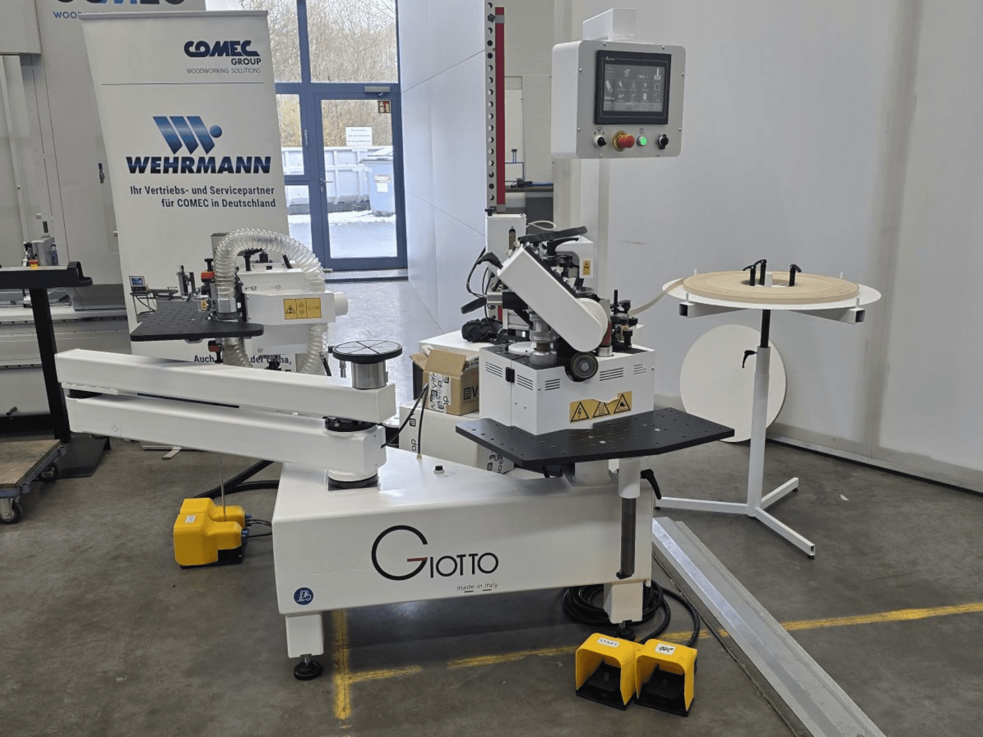 Máquina de processamento de madeira Giotto com painel de controlo, vista lateral, inclui pedais e superfície de trabalho rotativa.