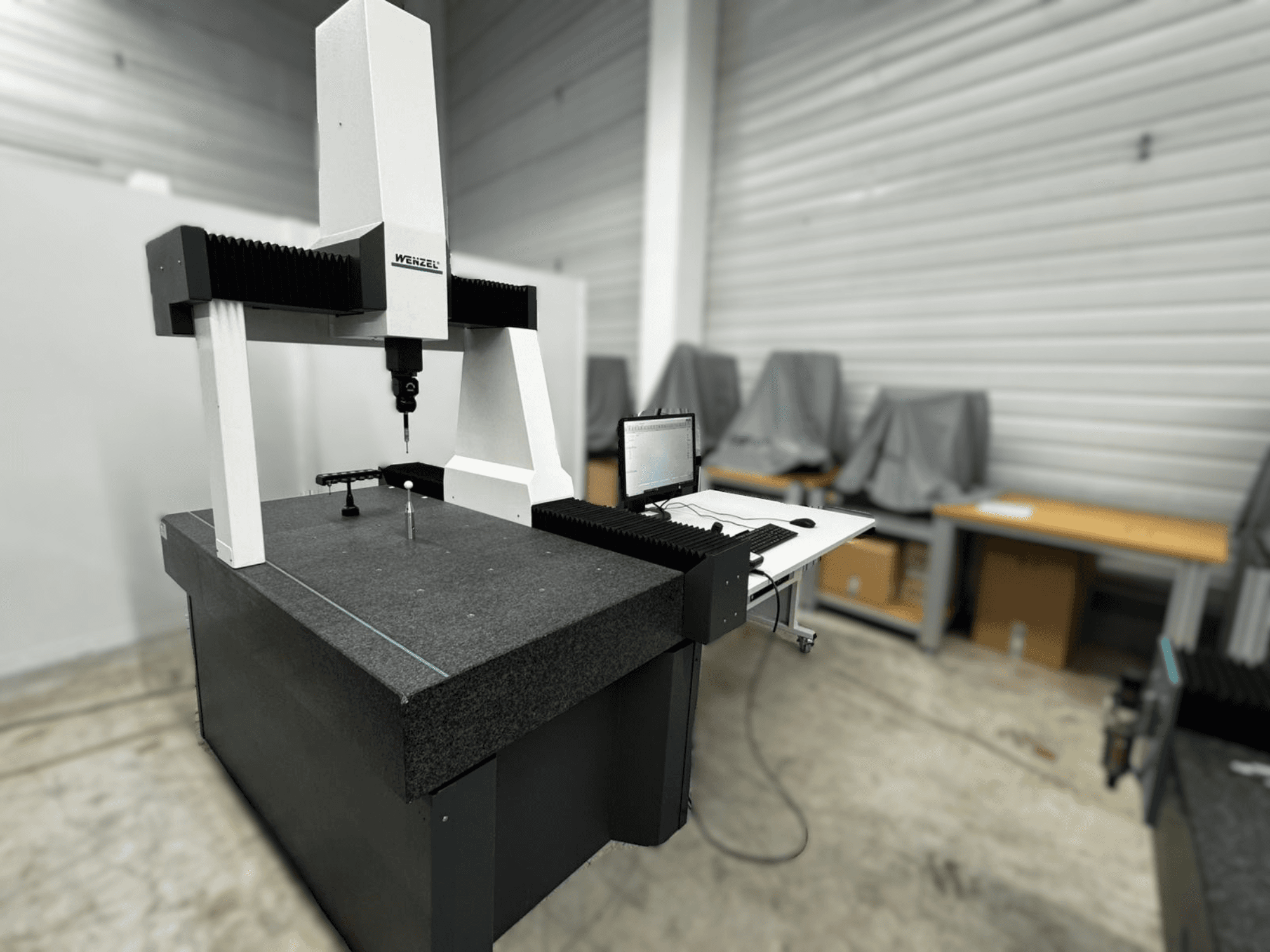 Máquina de medição por coordenadas Wenzel LH 54 em vista lateral, com uma sonda e uma interface de computador numa base cinzenta.