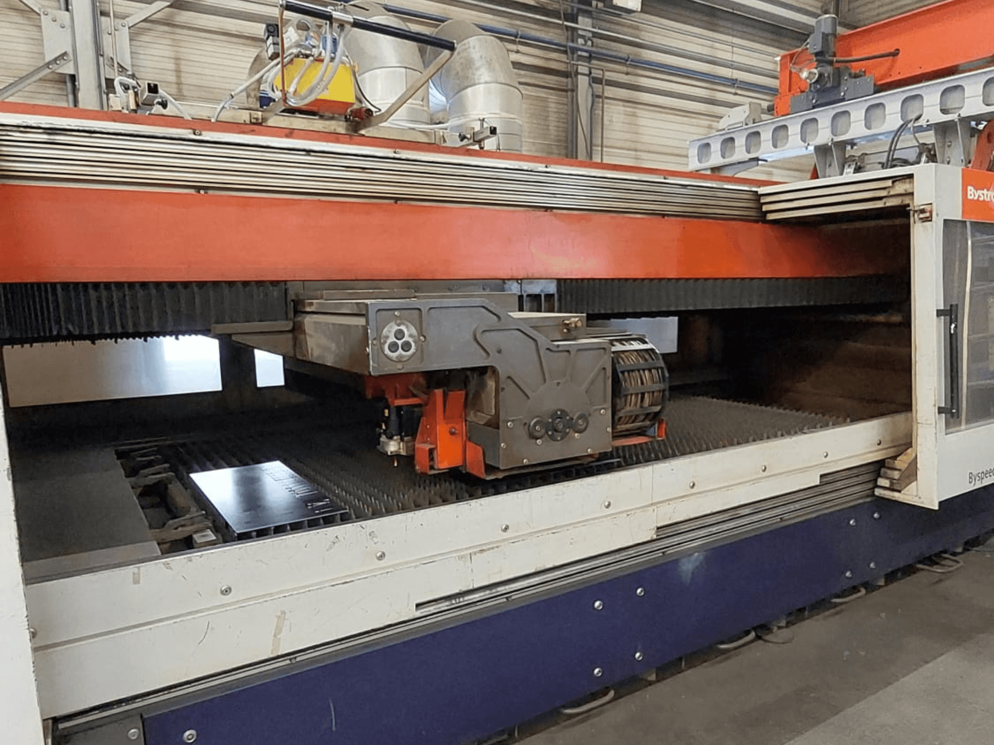 Máquina de corte a laser de CO₂ Bystronic BySpeed 3015, vista frontal que mostra a cabeça de corte e a chapa metálica na mesa de corte.