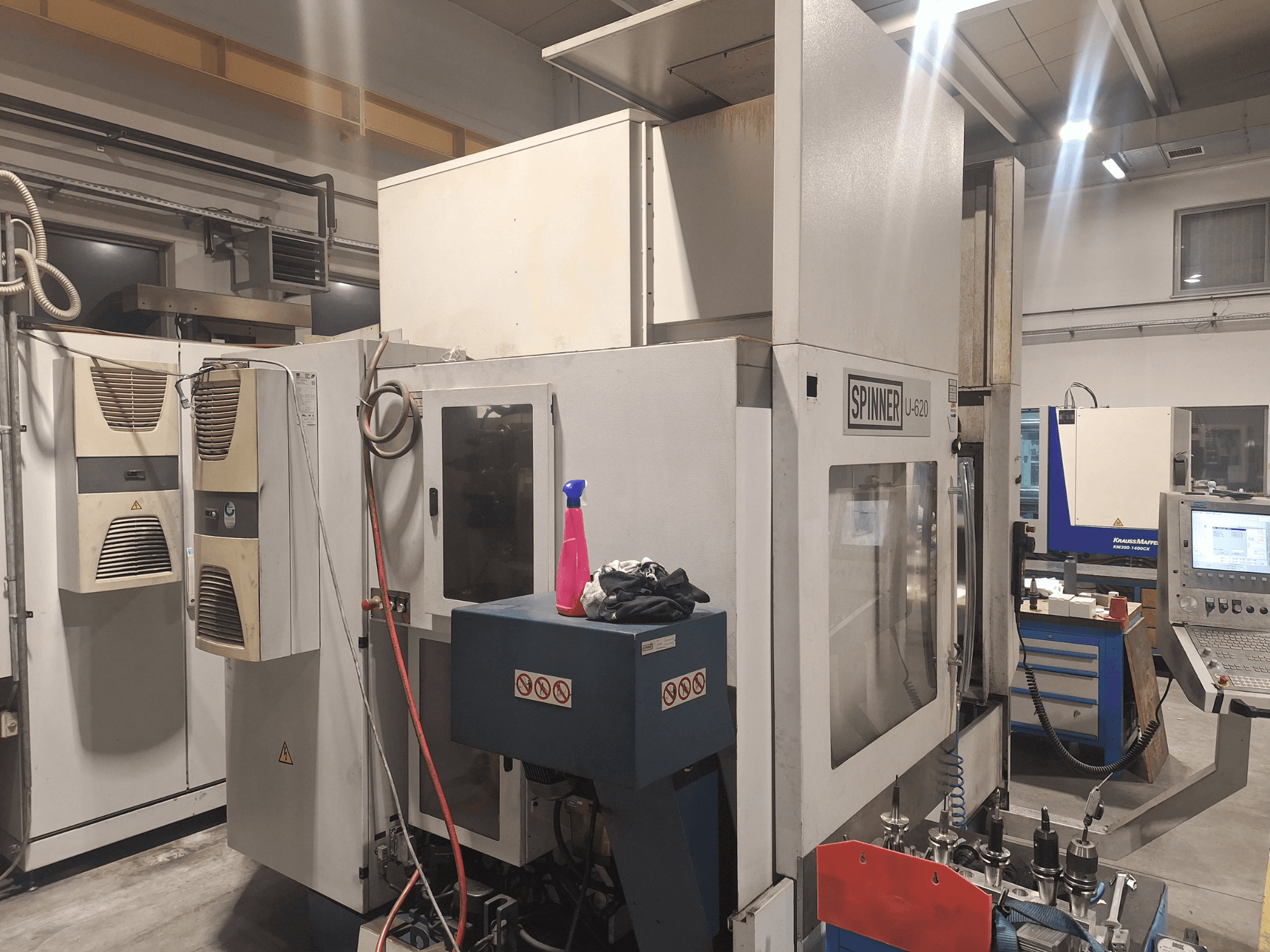 Máquina CNC Spinner U-620 vista de frente numa oficina, com painel de controlo e várias ferramentas numa bancada próxima.