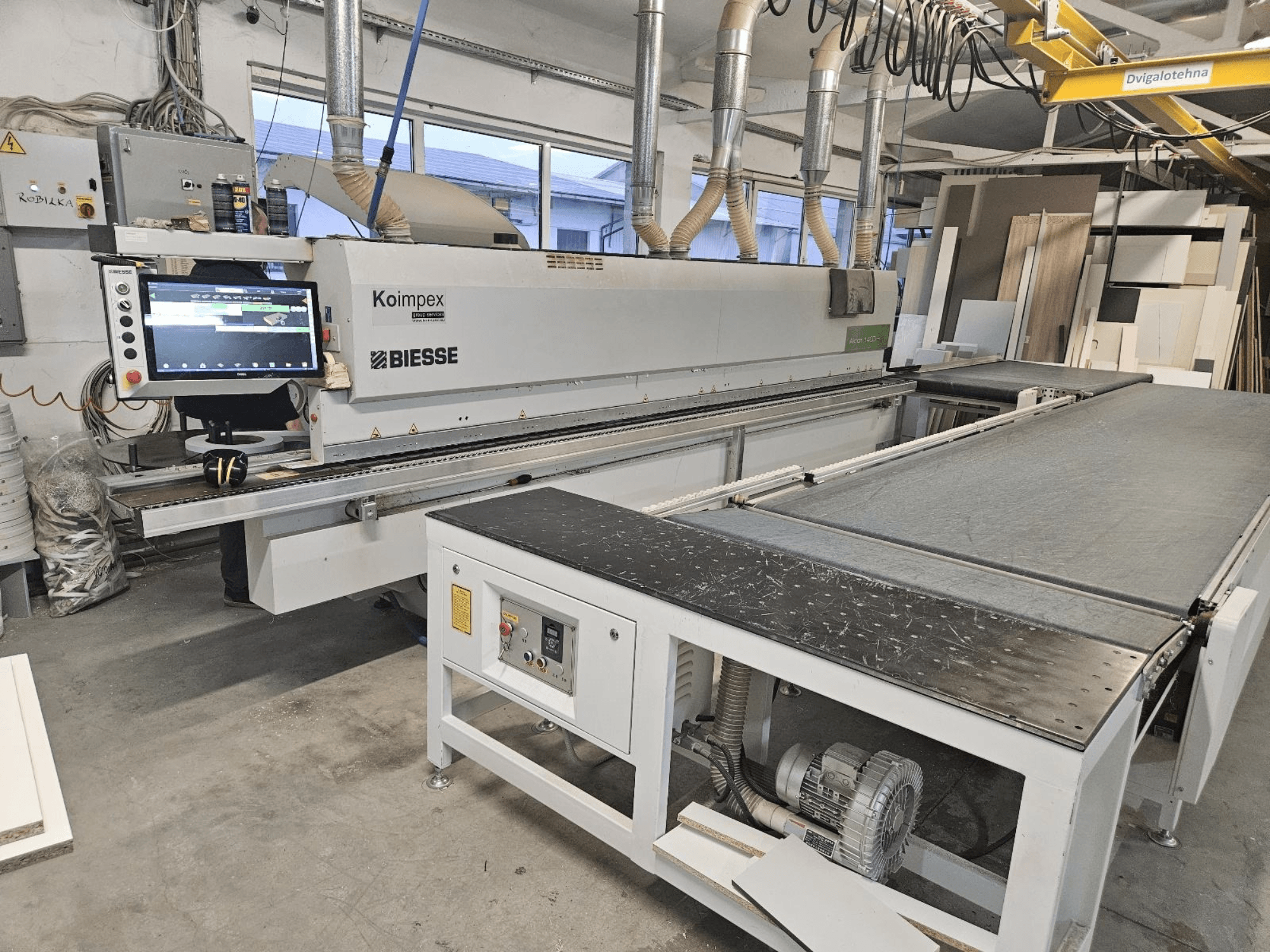 BIESSE Akron 1440 Uma orladora numa oficina, vista lateral mostrando o painel de controlo e o tapete transportador.