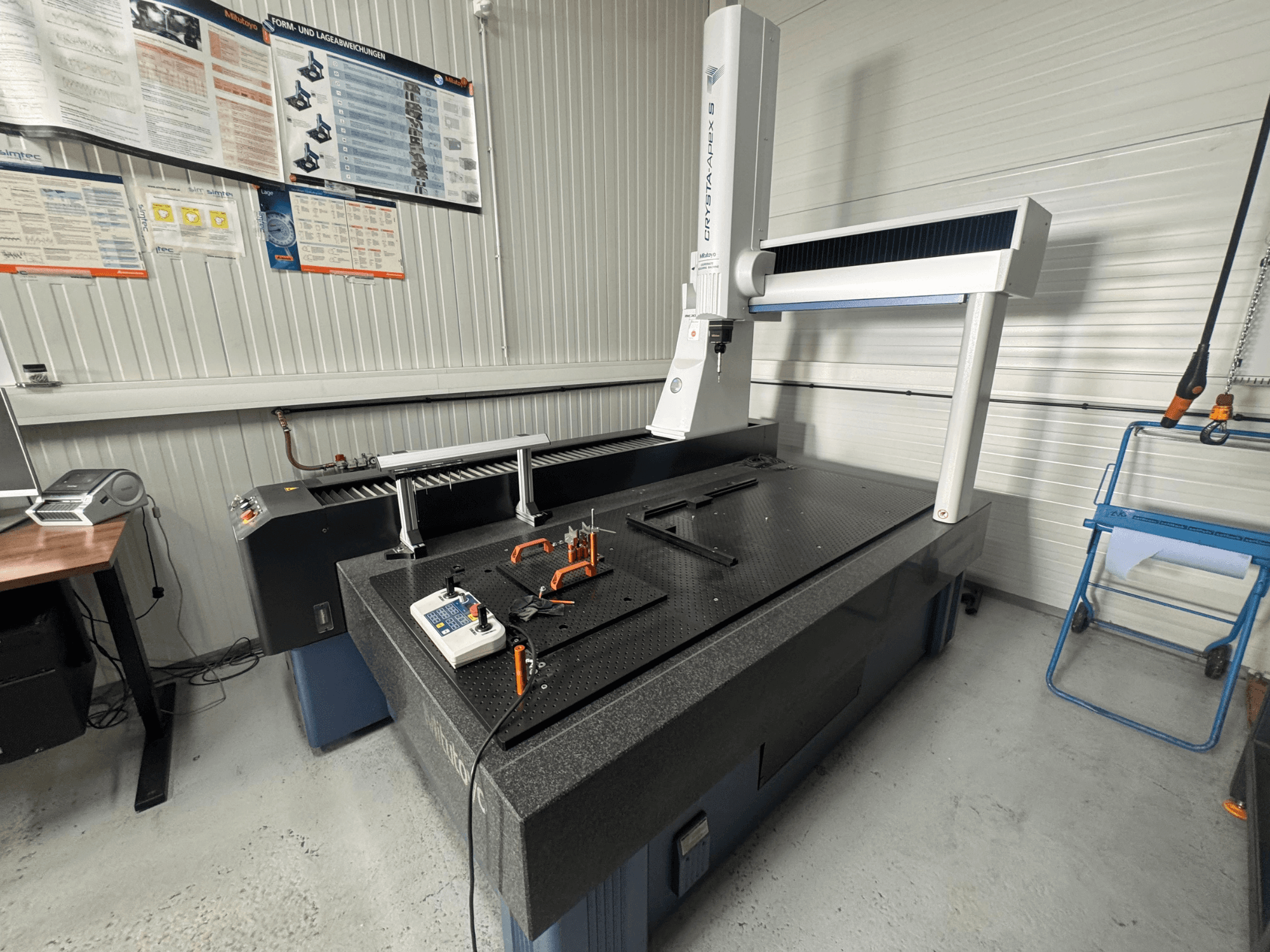 Máquina de medição por coordenadas CMM da marca Leitz, vista frontal sobre uma superfície preta texturada com ferramentas de medição.