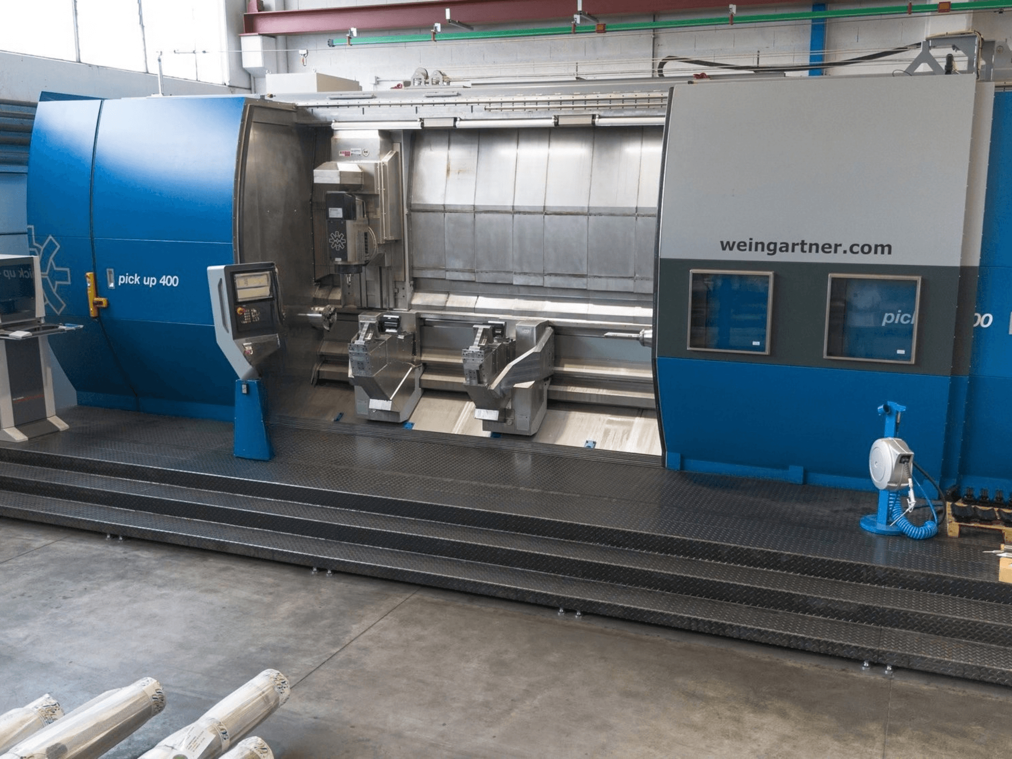 Centro de fresagem e torneamento Weingartner Pick Up 400, vista frontal. Apresenta duas estações de trabalho e um painel de controlo, num ambiente industrial.