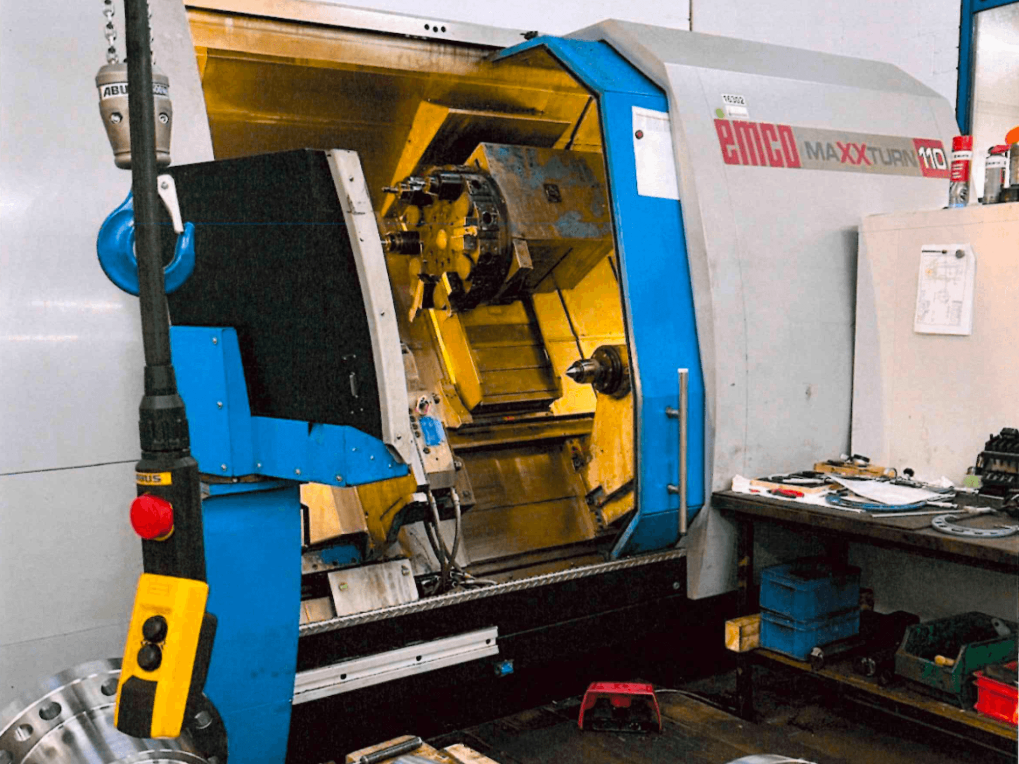 Torno horizontal EMCO MAXTURN 110, vista frontal, mostrando os componentes internos e o painel de controlo, num ambiente de oficina.