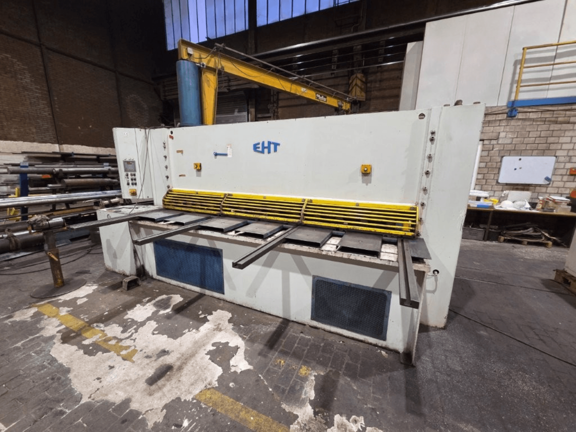 Máquina de cisalhamento hidráulico EHT vista de frente, com proteção de segurança amarela e painel operacional com controlos.
