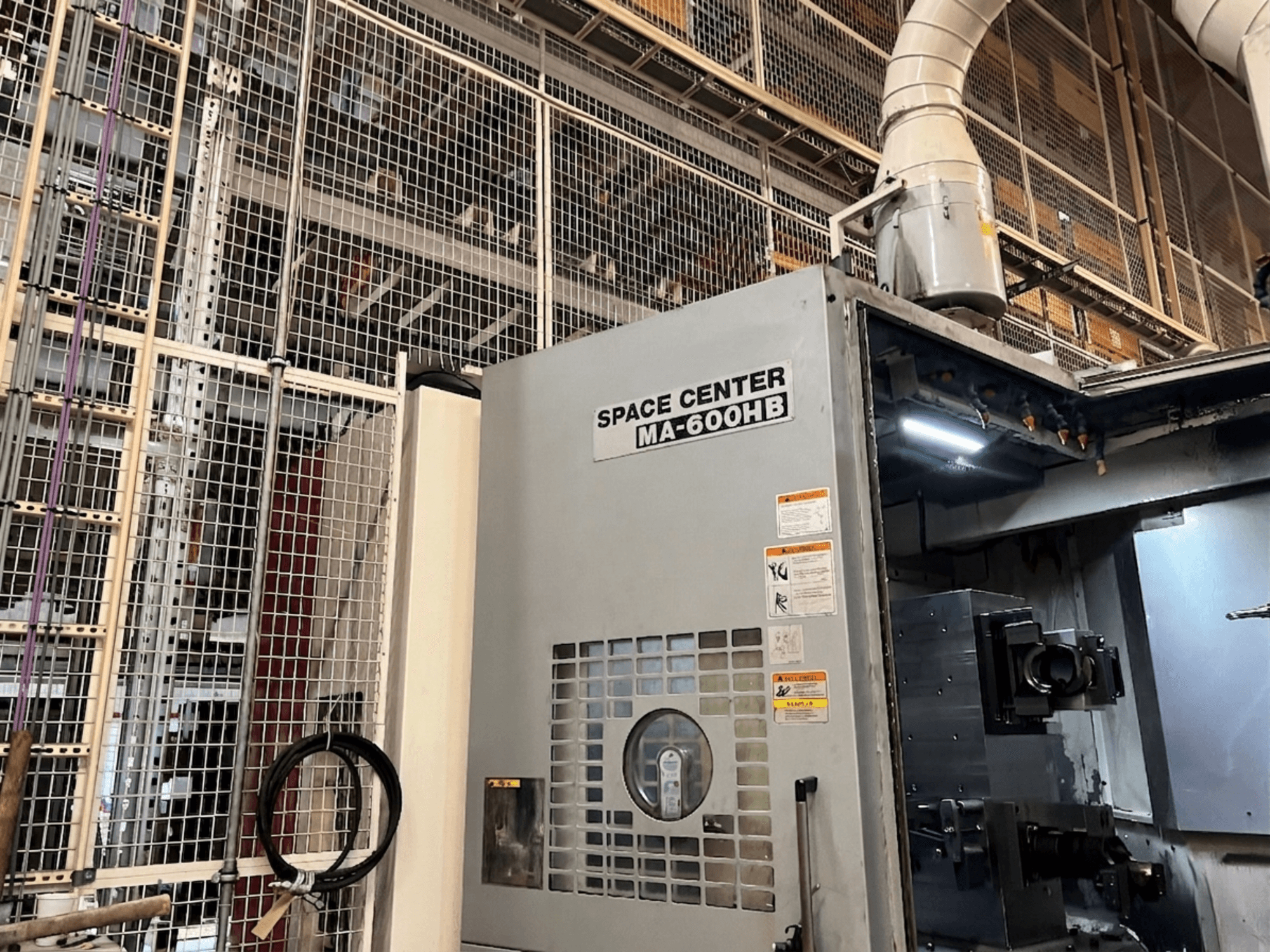 Centro de maquinação horizontal Okuma MA-600HB, vista frontal, com painel operacional e bicos de refrigeração visíveis.