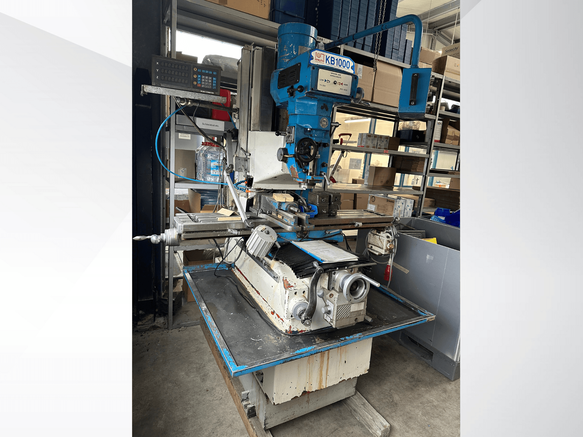 Fresadora vertical KB1000 com ecrã digital, vista lateral mostrando a mesa, o fuso e o porta-ferramentas.