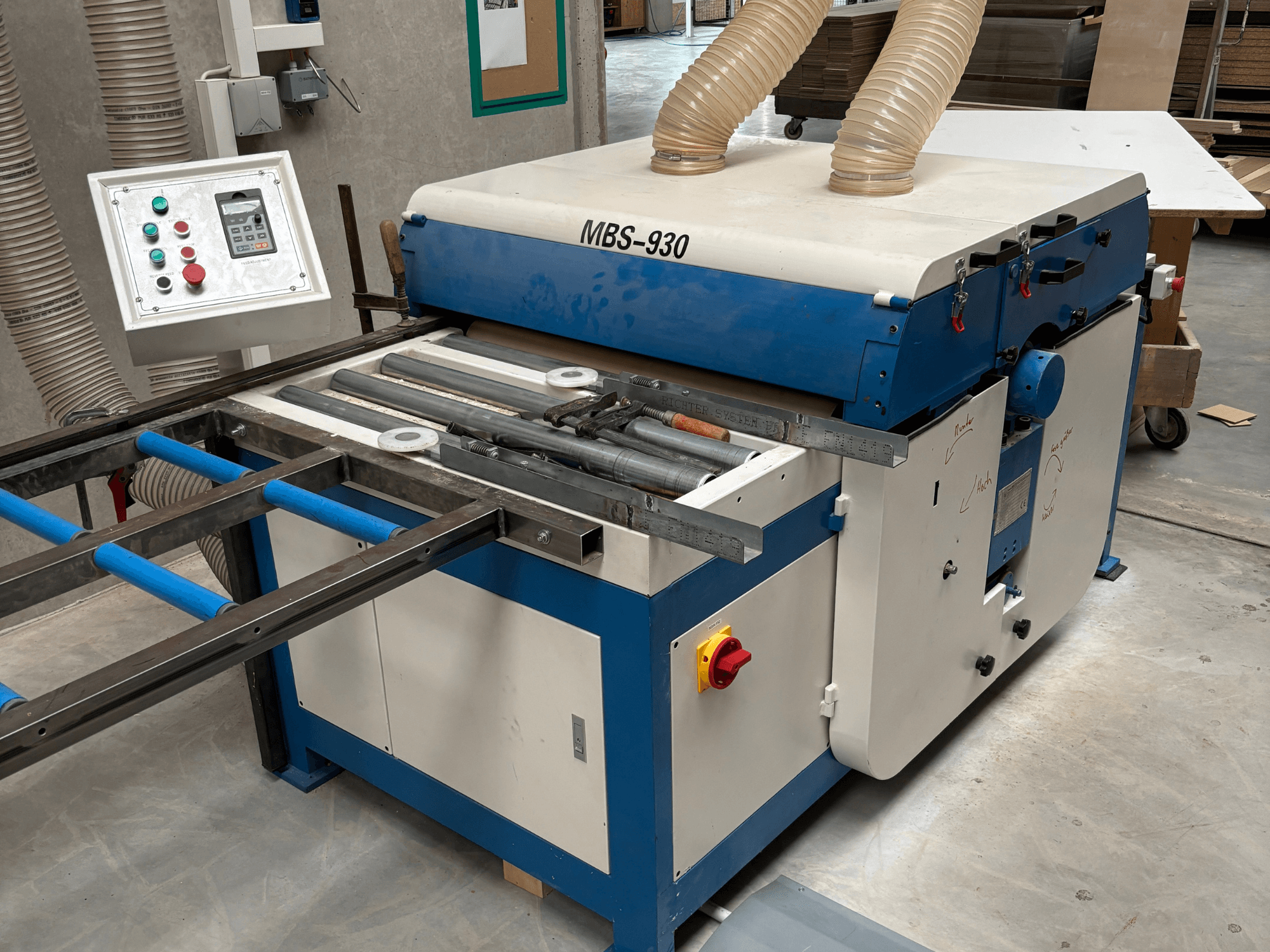 Máquina para trabalhar madeira MBS-930 com painel de controlo e rolos, vista de lado, com mangueiras de extração de pó.