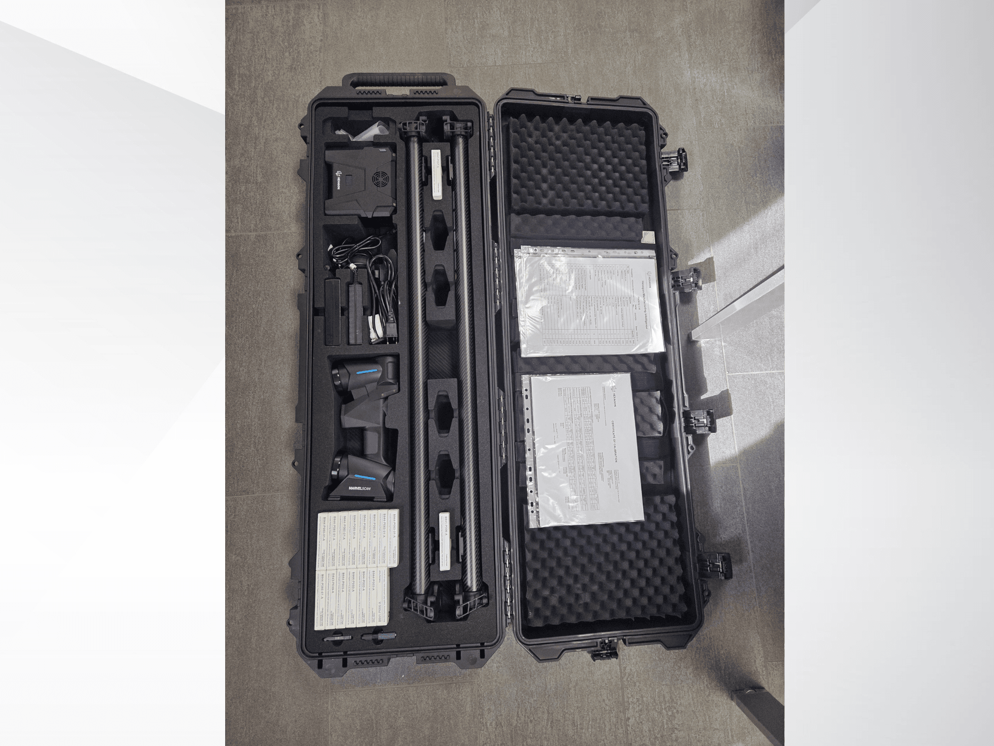 Equipamento CMM Hexagon MARVEL numa mala preta, com vários sensores, cabos e documentação; vista de cima para baixo.