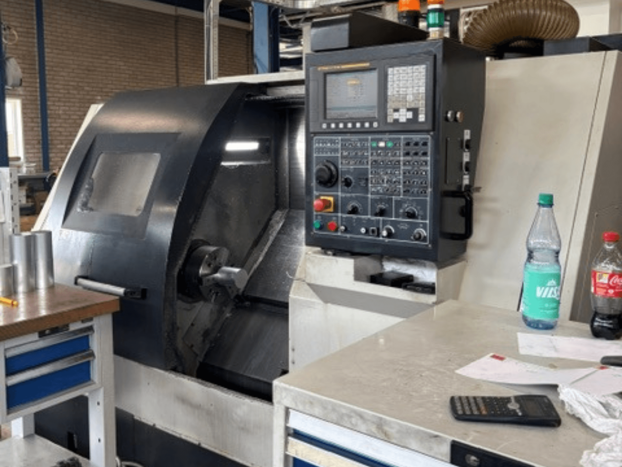 Torno horizontal Leadwell T-7, vista frontal, com painel de controlo, peça de trabalho no apoio de ferramentas e detalhes da área de trabalho visíveis.