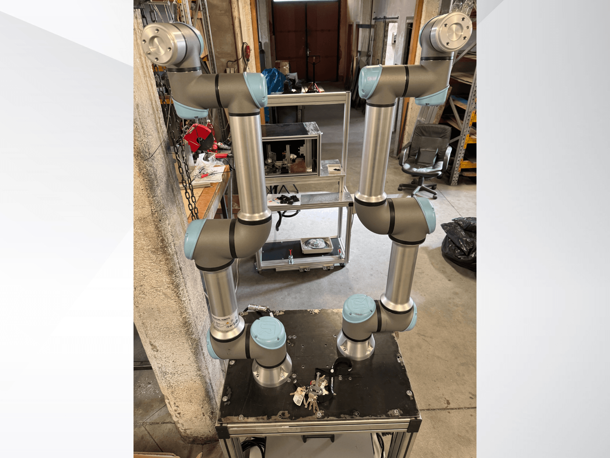 Braço do robô Universal Robots UR5e mostrado de frente, com seis articulações com secções cinzentas e azuis, montado numa plataforma preta.