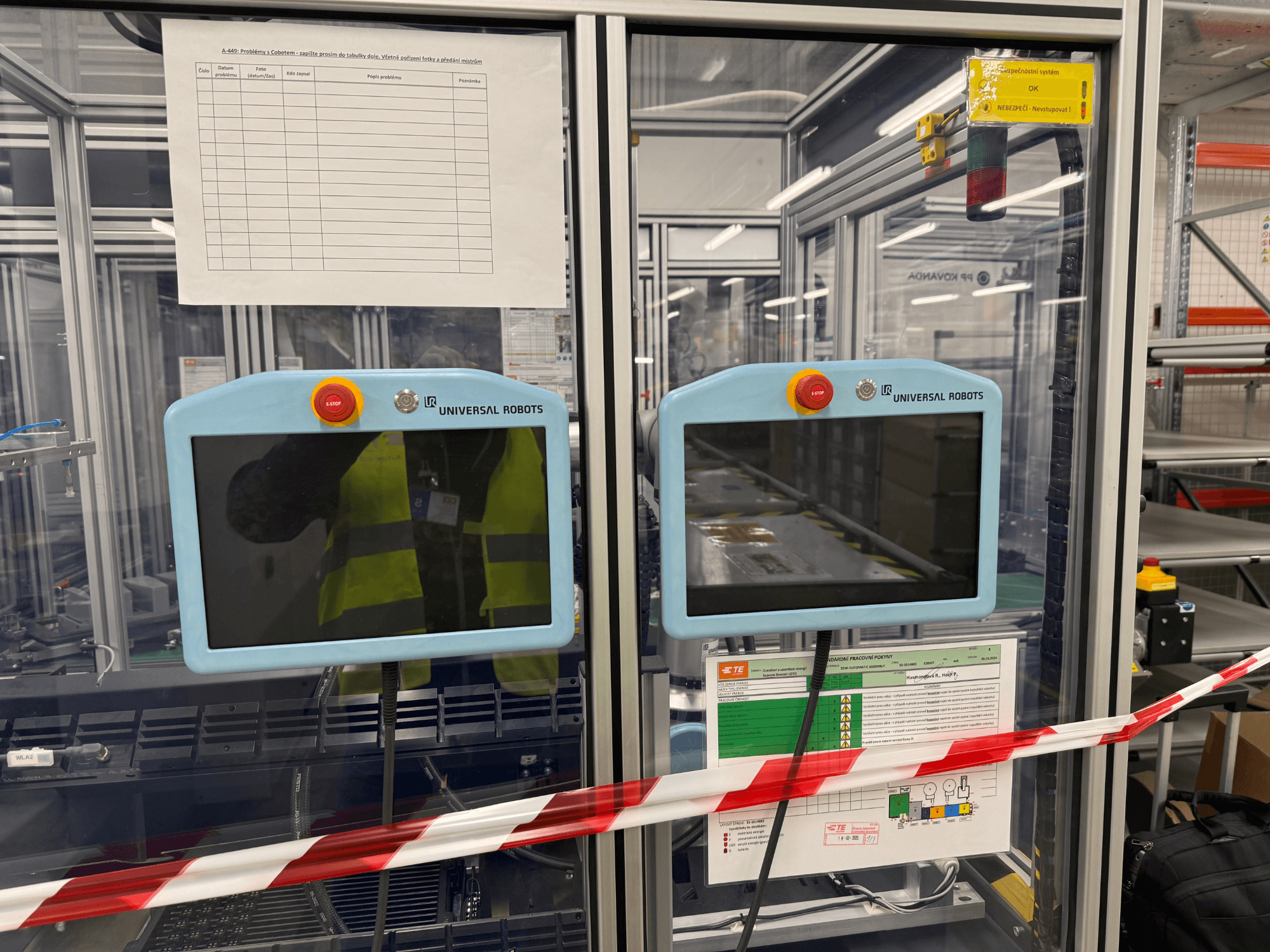 Painel de controlo para o braço robótico Universal Robots UR5 e, com dois monitores, botões de paragem de emergência e instruções de segurança.