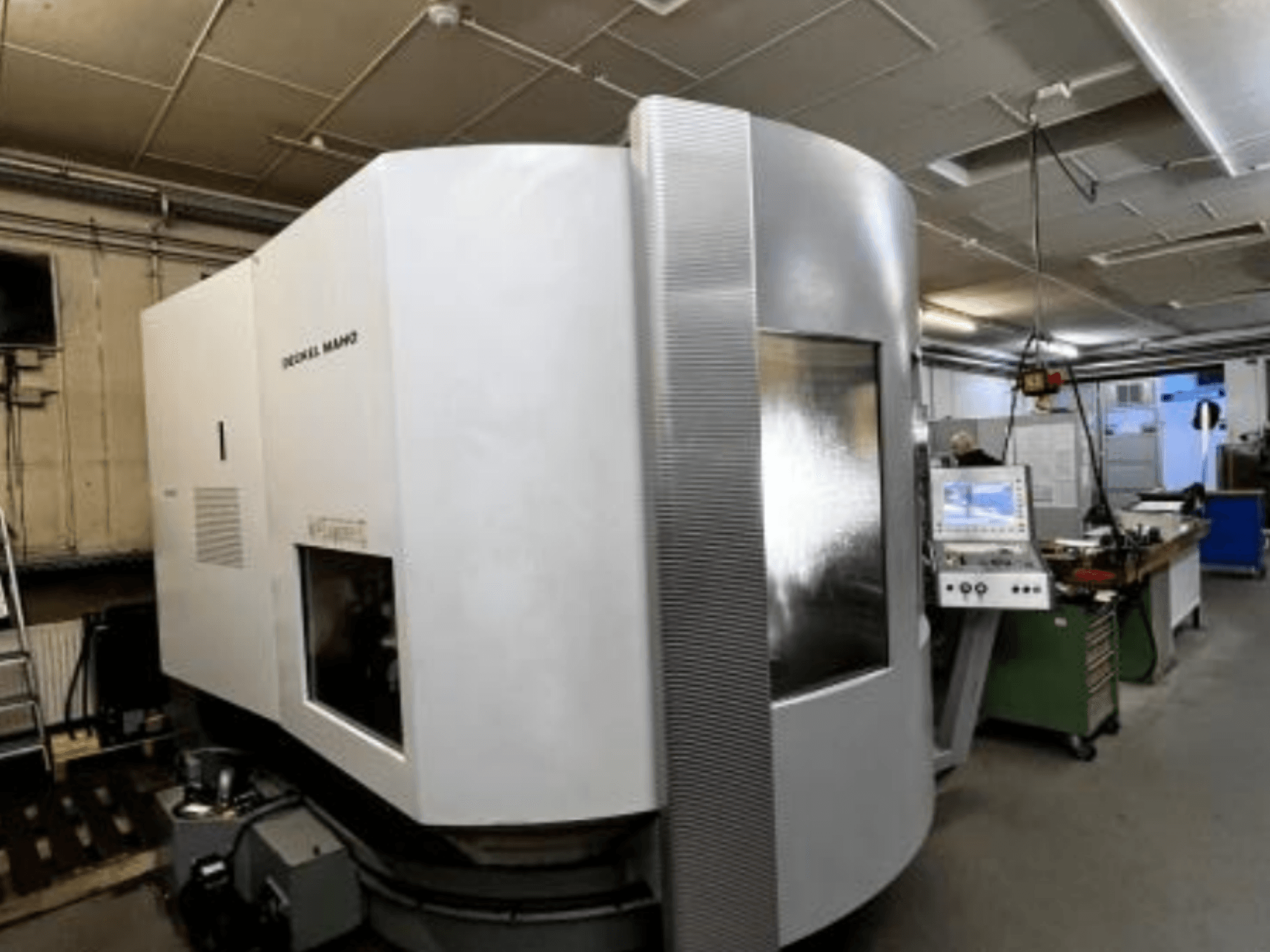 Máquina CNC SODICK MAKO numa oficina, vista lateral, com painel de controlo e área de trabalho visíveis em segundo plano.