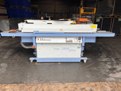 Hebrock Top 2000 Plus, vista frontal; máquina eléctrica industrial com painel de controlo, rodas para mobilidade e etiquetas de segurança visíveis.